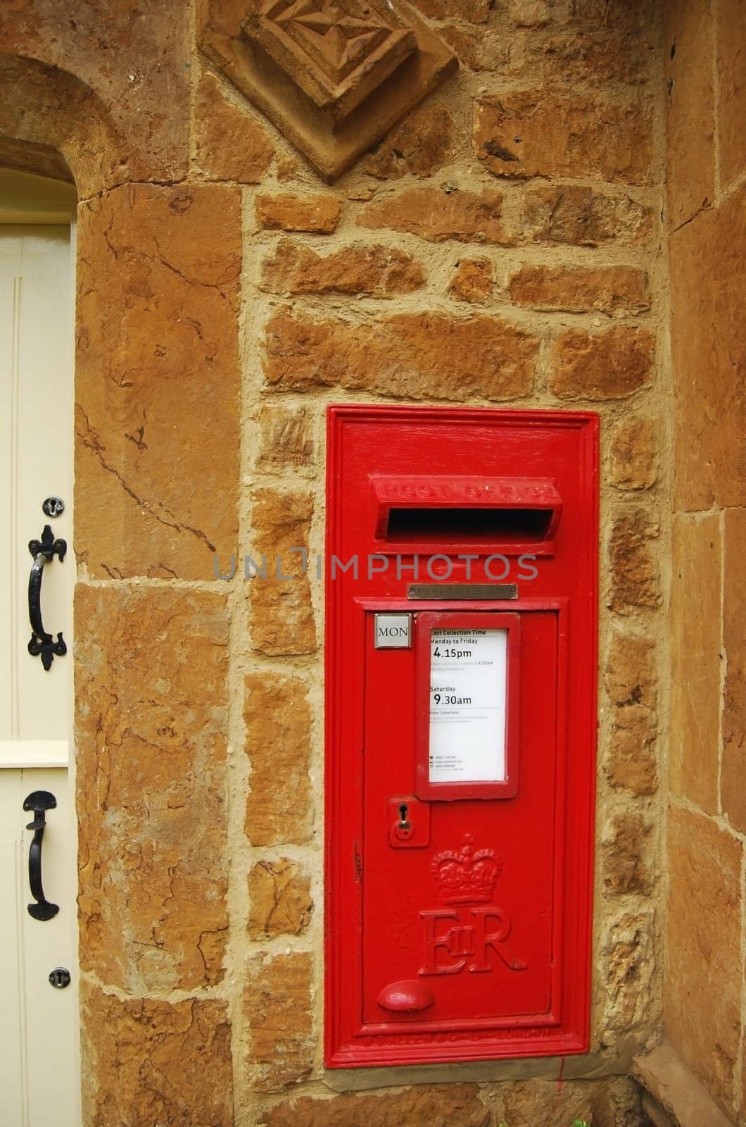 Red british post box on stone wall by varbenov