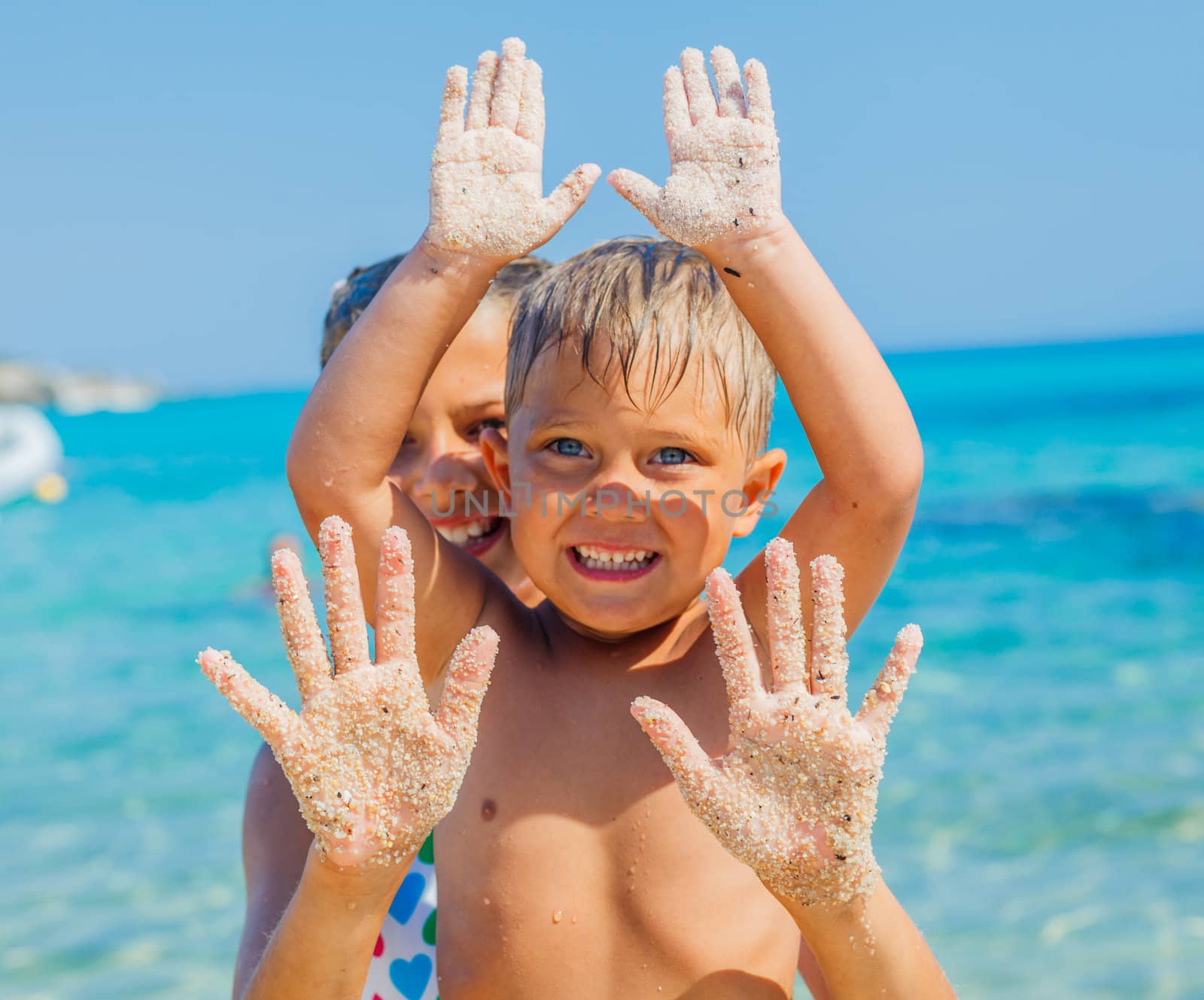 Close-up view of hands by the girl and boy on the sand beach.