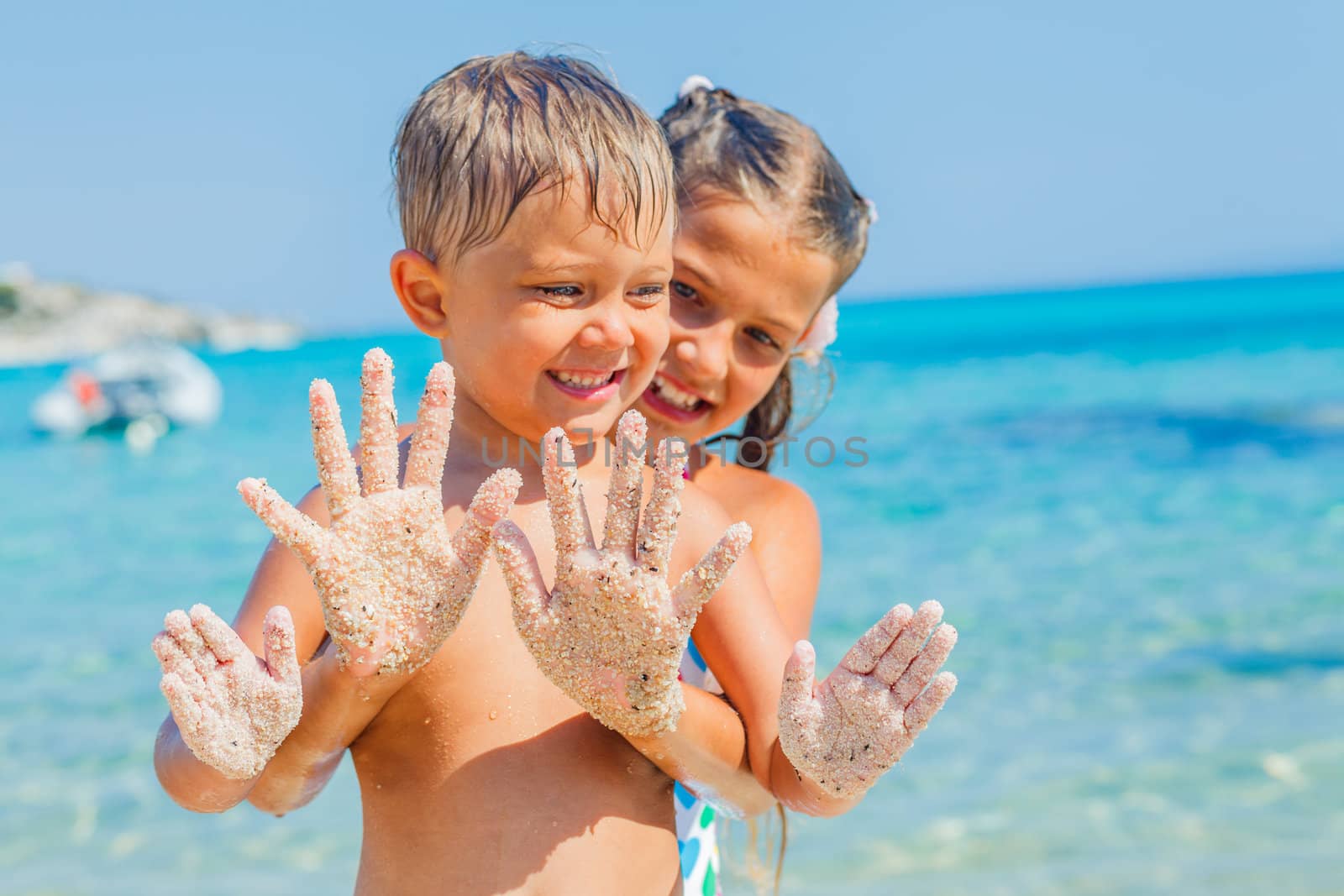 Close-up view of hands by the girl and boy on the sand beach.