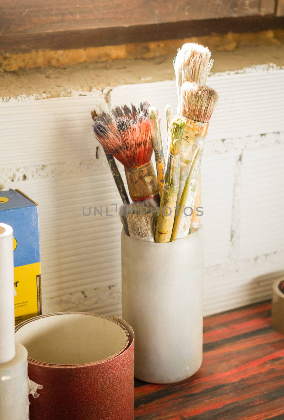 Set of paint brushes on jar, in a artistic red table