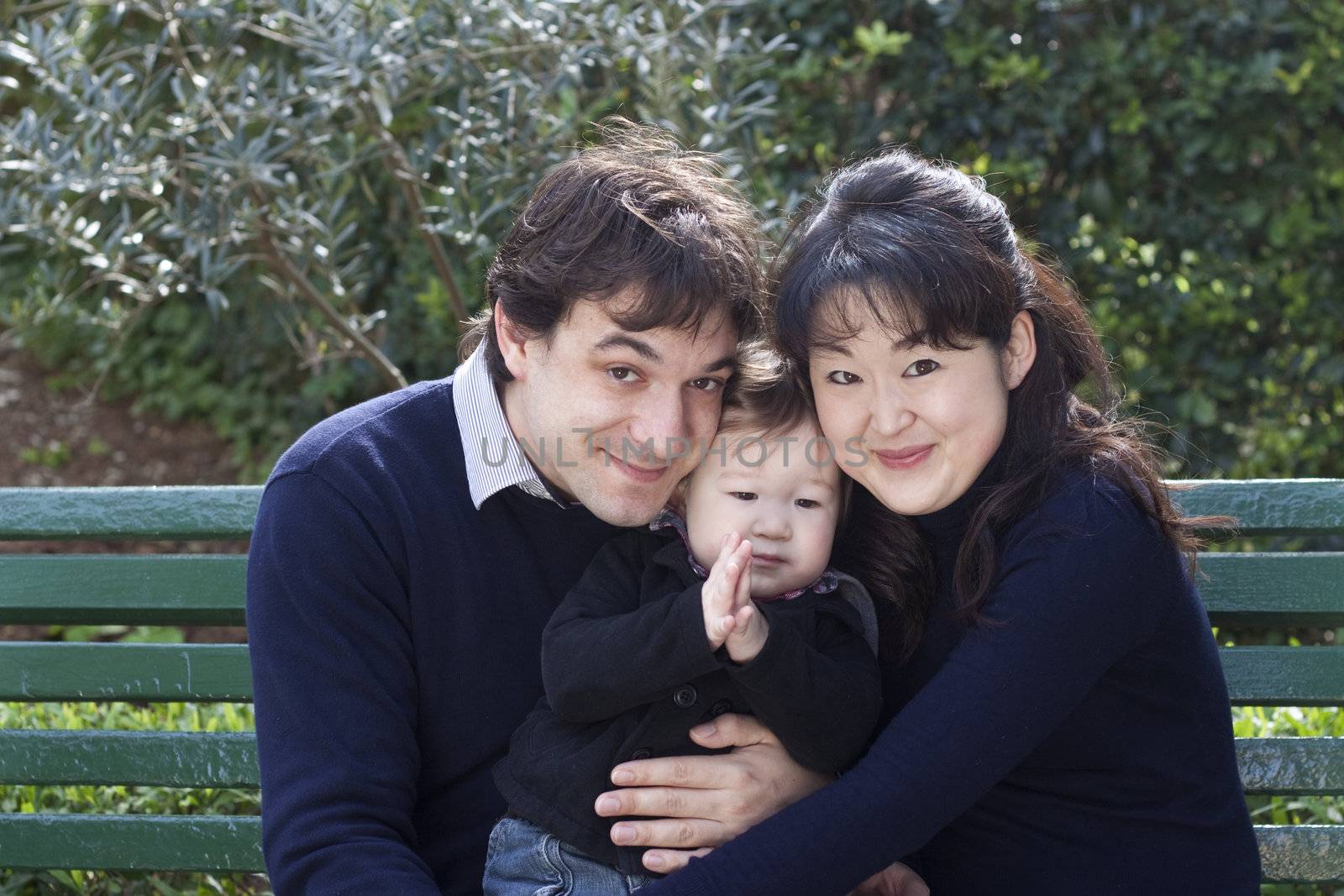 French father and Japanese mother with their baby boy in a park 