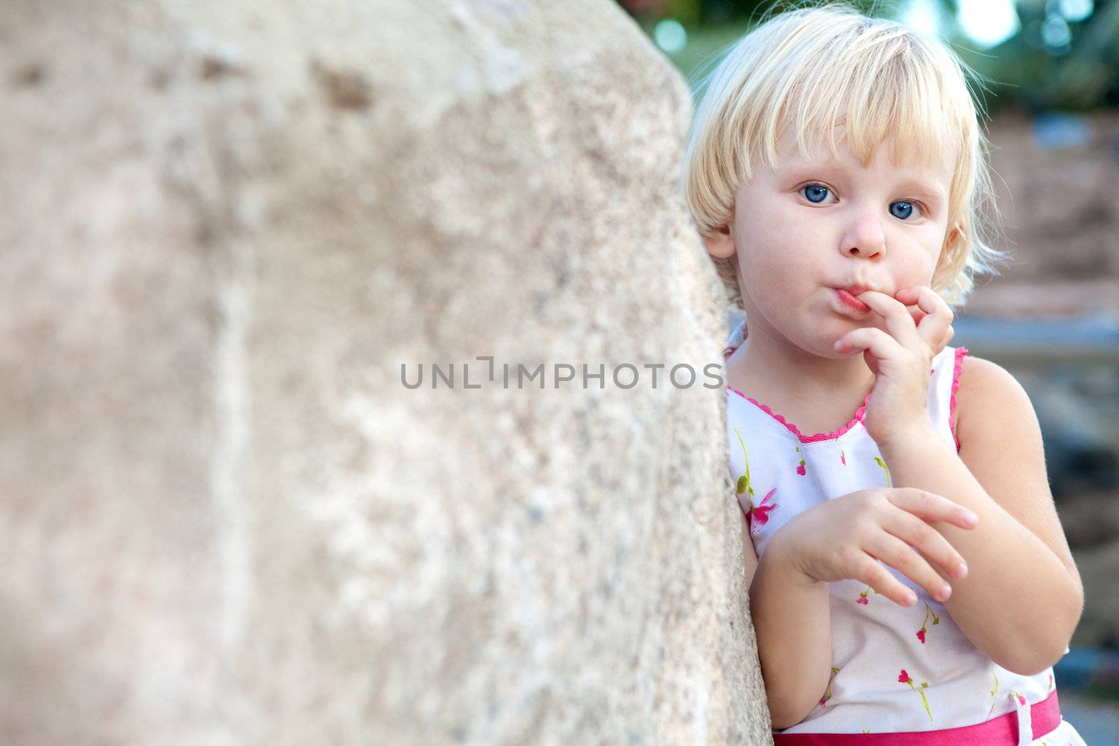surprised girl sucking finger by the stone