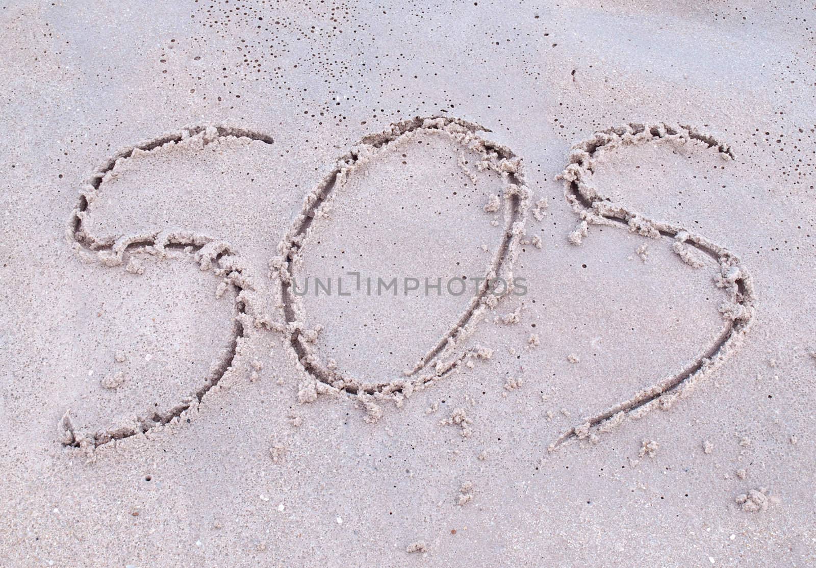 SOS(save our souls) drawn on the sand in tropical beach