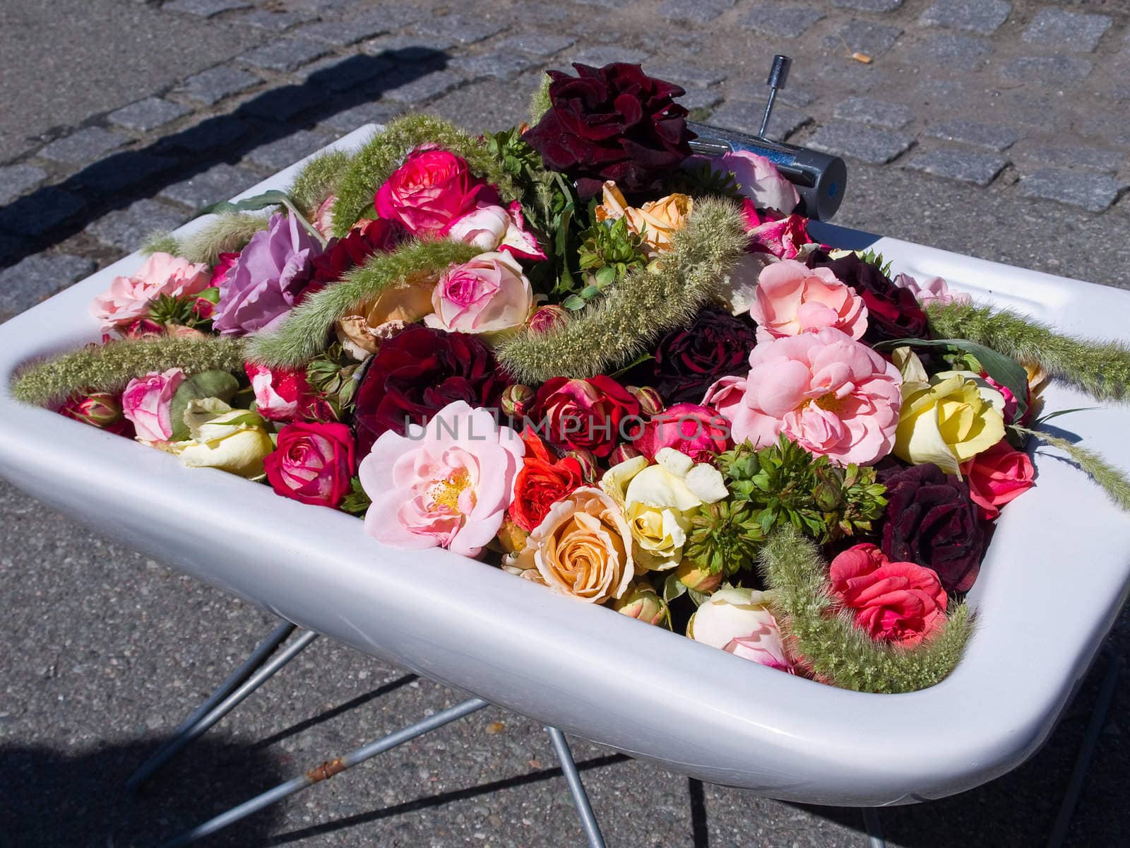 Street decoration roses and flowers arranged in an old white  sink