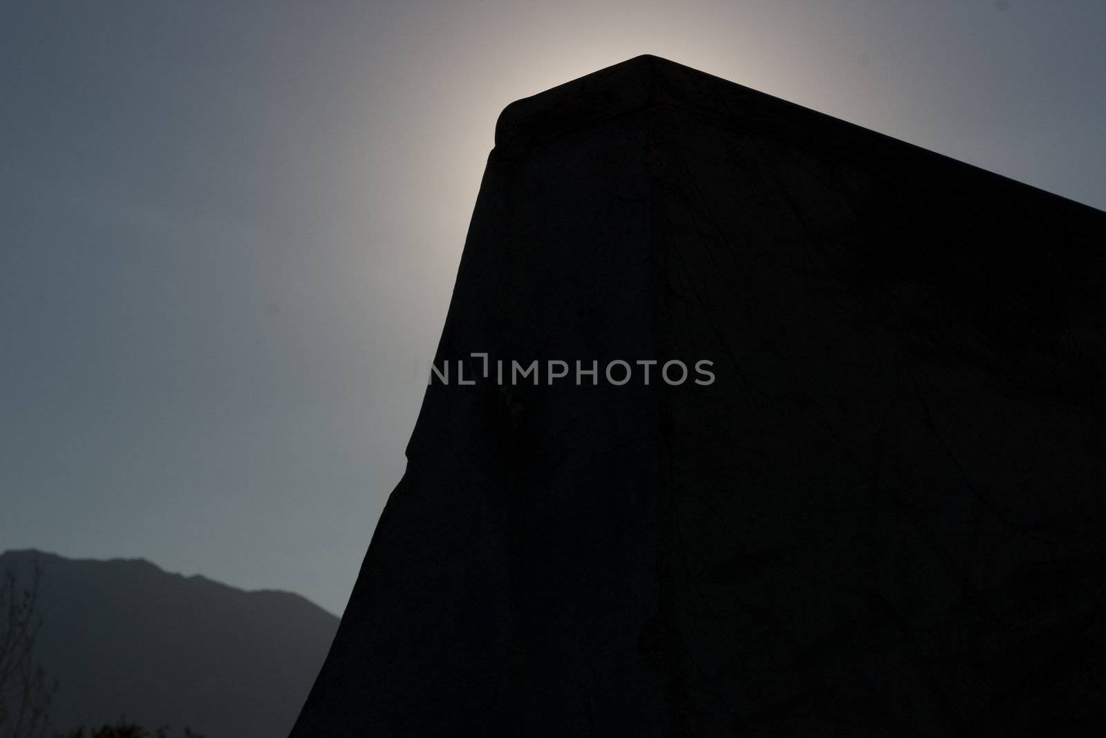 silhouette of a quarter pipe at a skate park with mountains in background