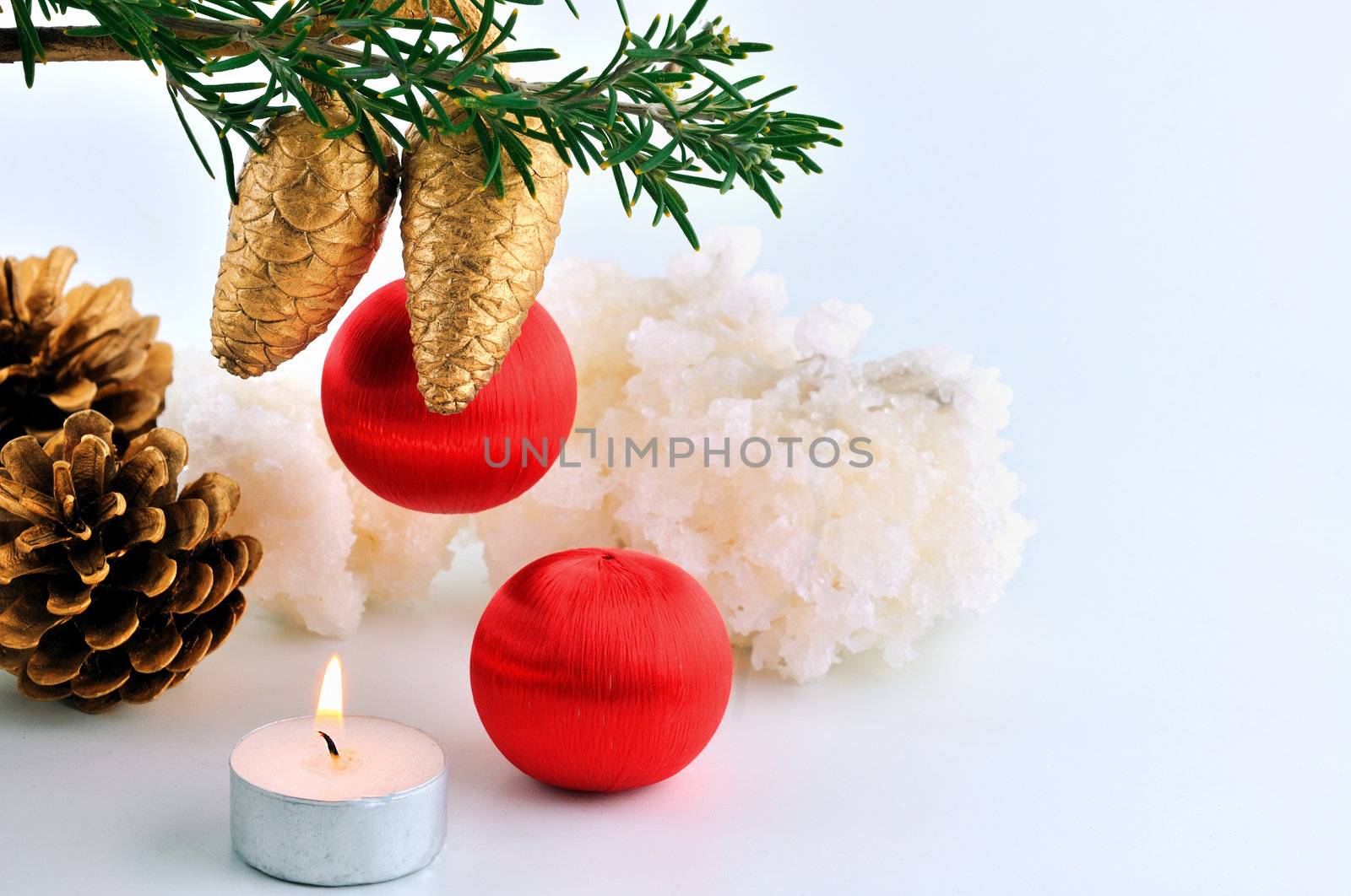 Red balls, cone spruce,  and sprigs to decorate for Christmas against a white background and candles burning