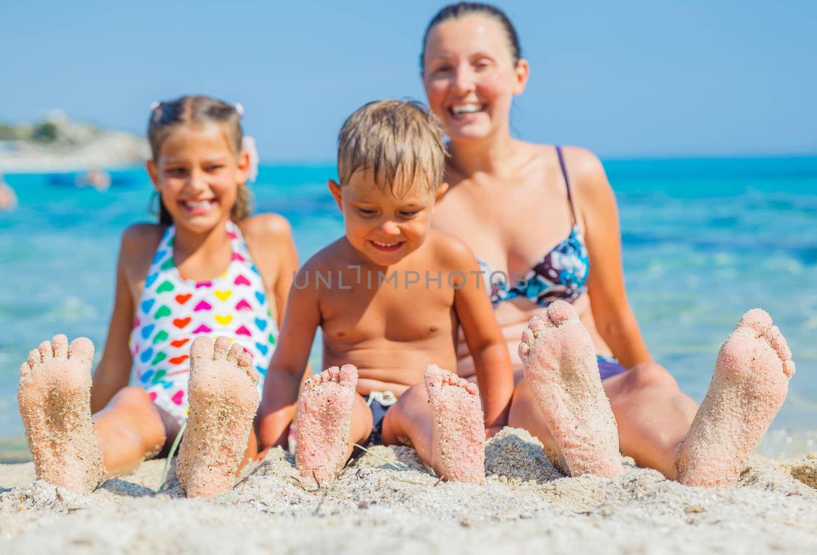 Summer beach - family playing on sandy beach. Focus on the feet