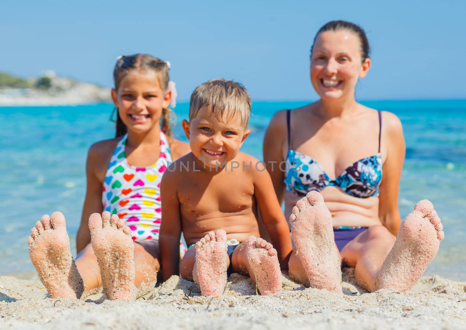 Summer beach - family playing on sandy beach. Focus on the feet and boy.