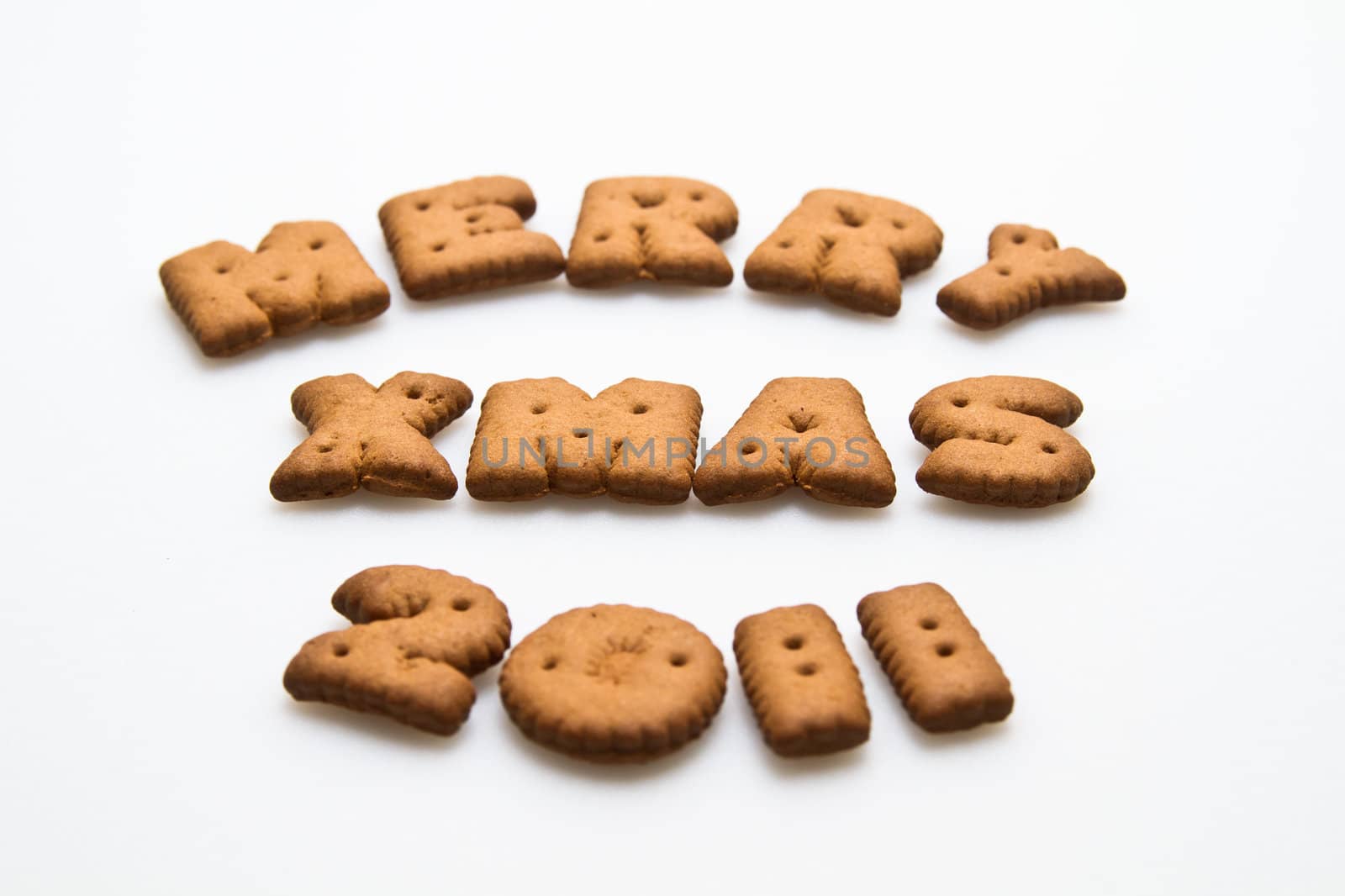 Merry Xmas 2011 wording from brown biscuits slanting view at center frame on white background  in landscape orientation