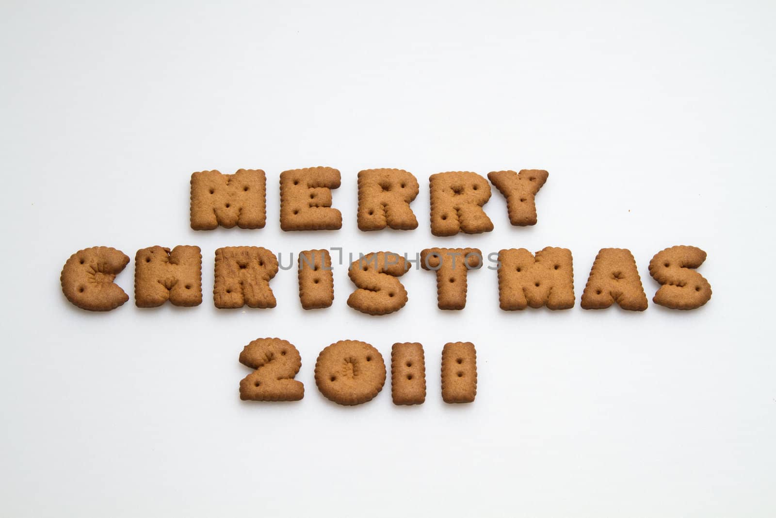 Merry Christmas 2011 wording from brown biscuits at center frame on white background  in landscape orientation