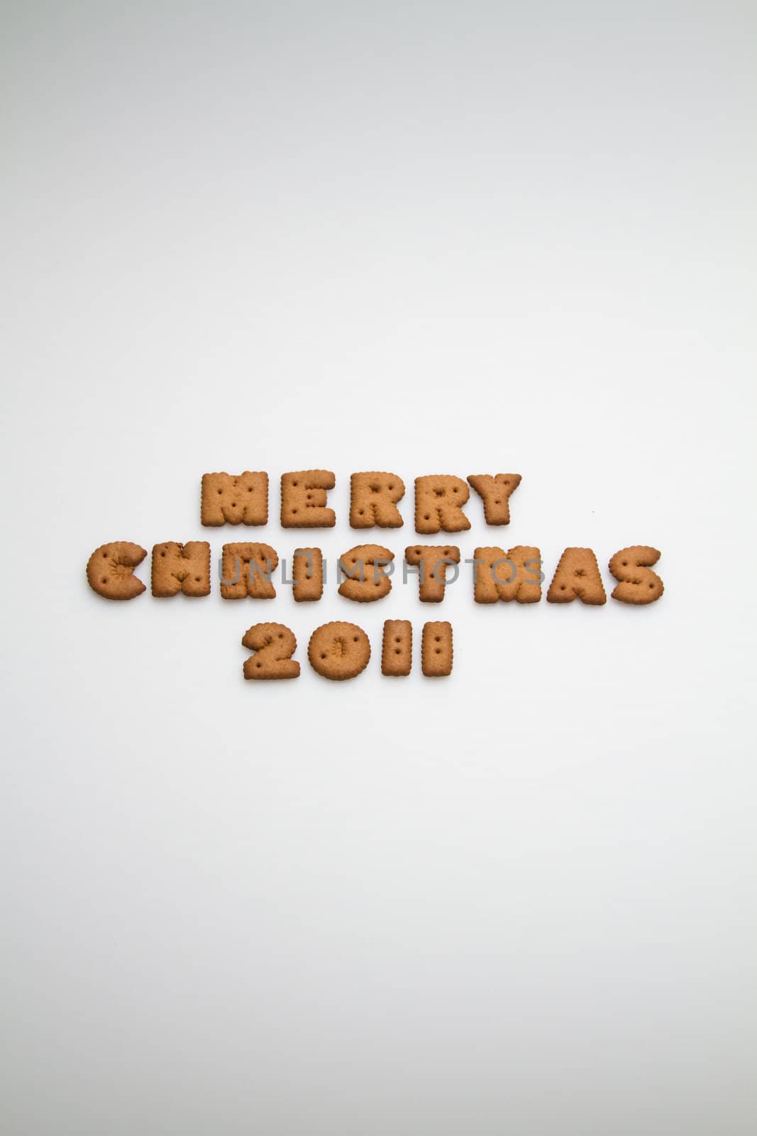 Merry Christmas 2011 wording from brown biscuits at center frame on white background  in portrait orientation