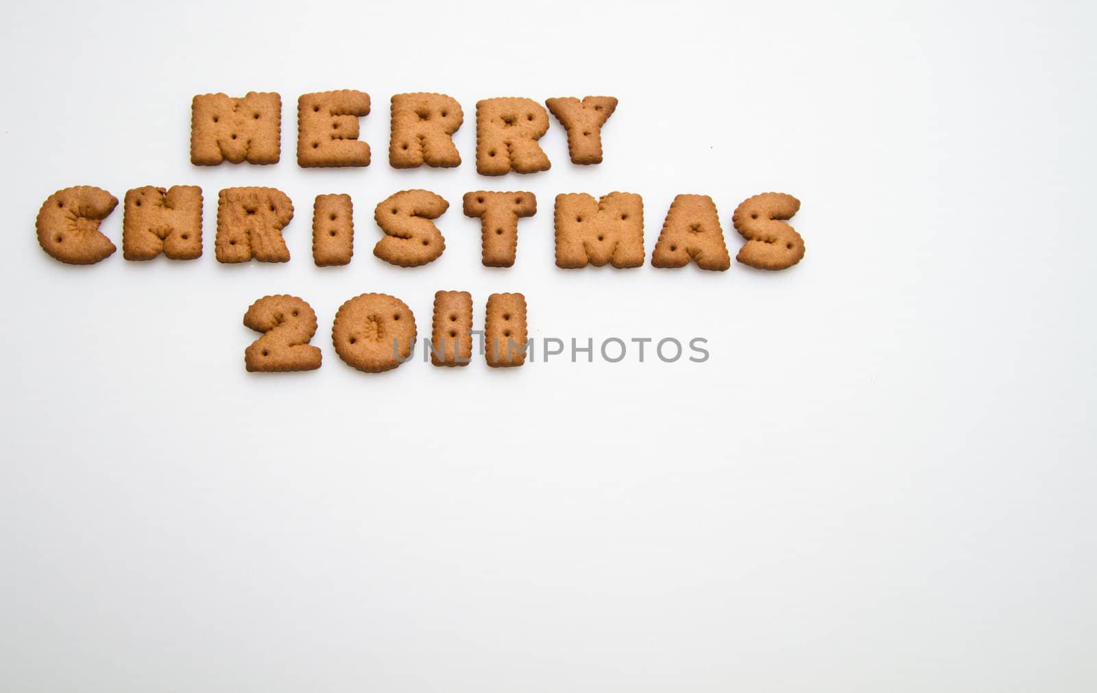 Merry Christmas 2011 wording from brown biscuits on white background at top left corner in landscape orientation