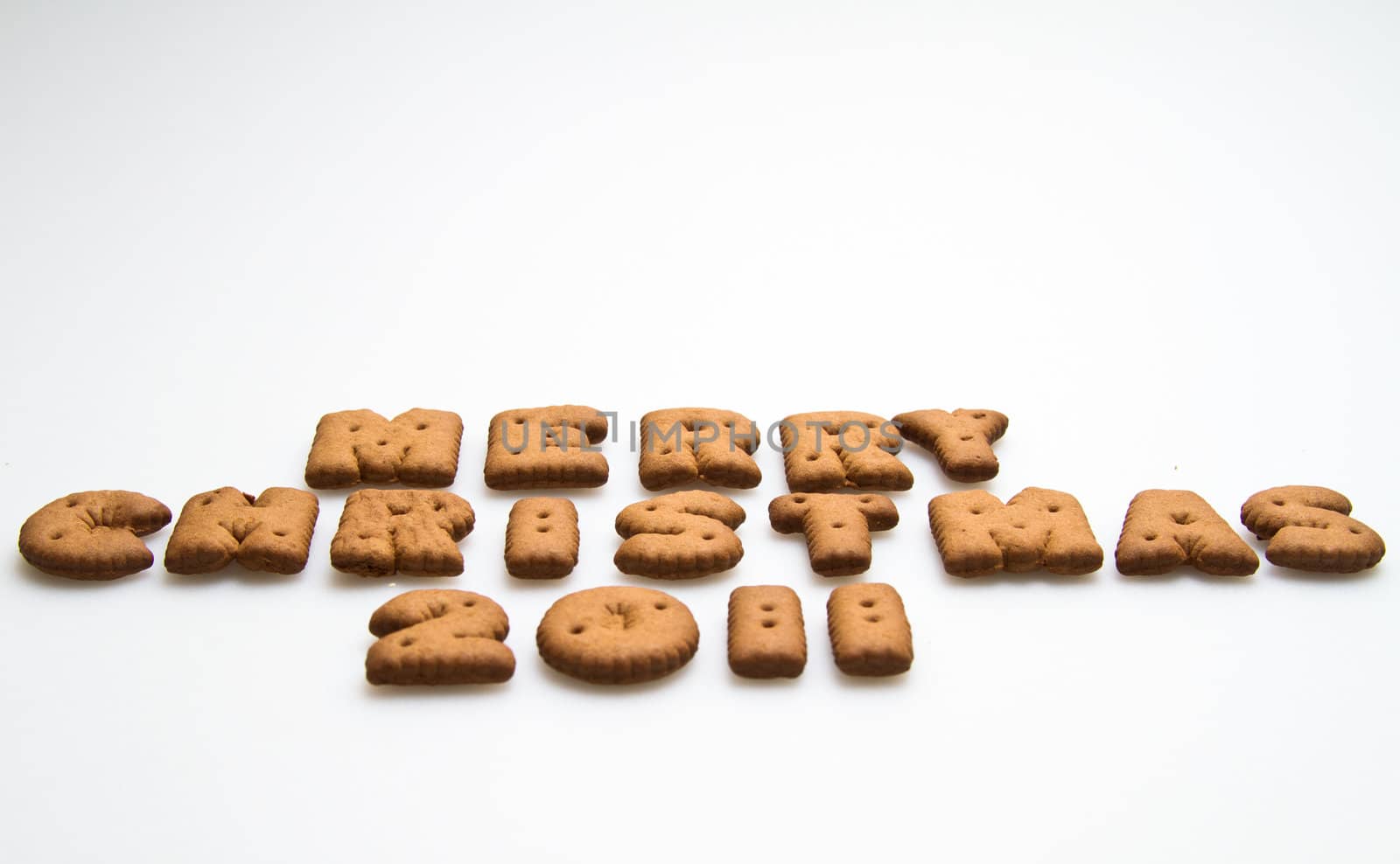 Merry Christmas wording from brown biscuits on white background laying in landscape orientation