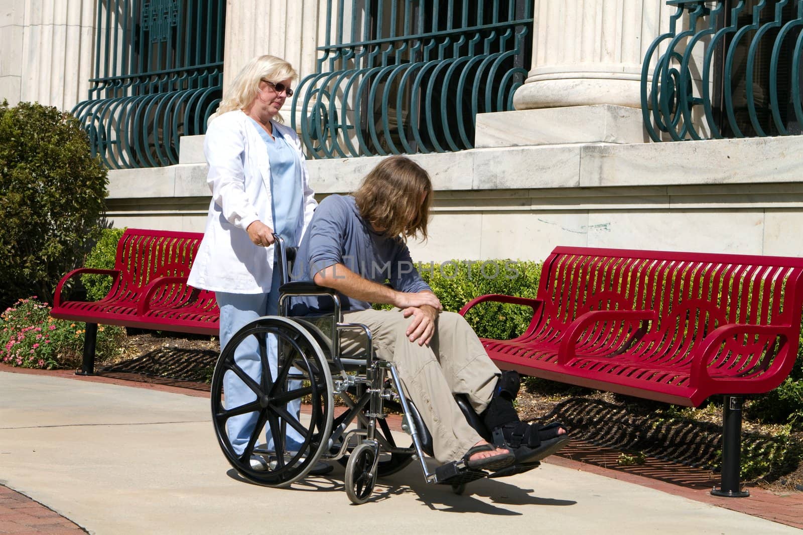 Nurse caregiver looks after a disabled psychopathic patient outside a state hospital facility for the mentally insane.