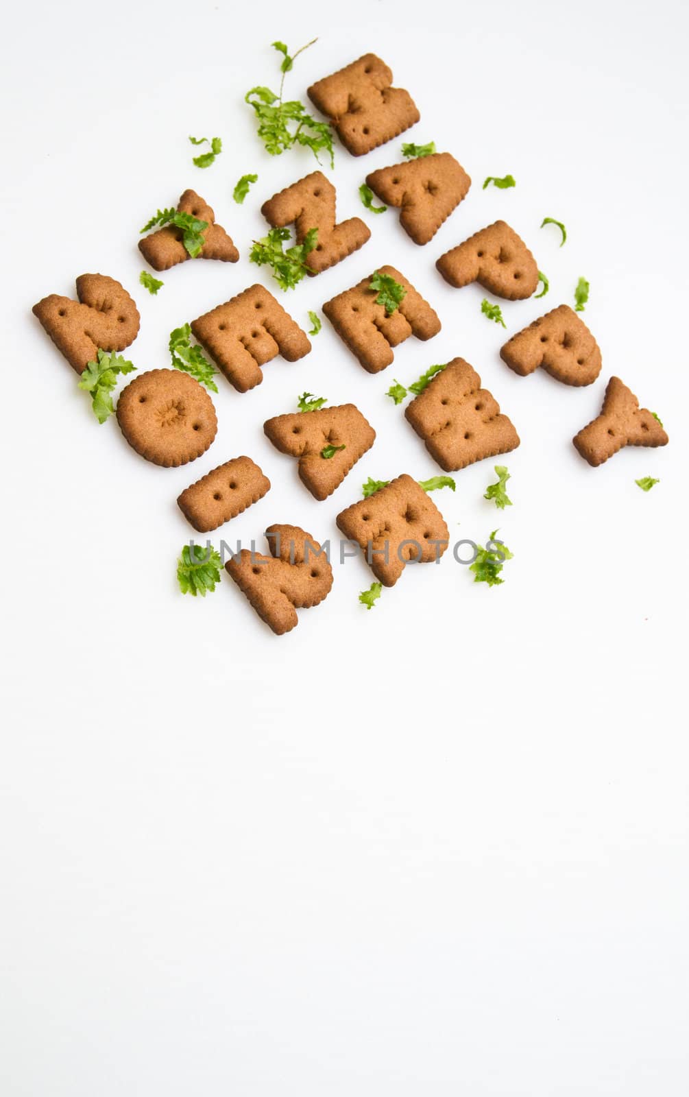 Angled view of Happy New Year greeting words made by brown biscuits with green leaves and copy space on upper center of white surface in portrait orientation for background use
