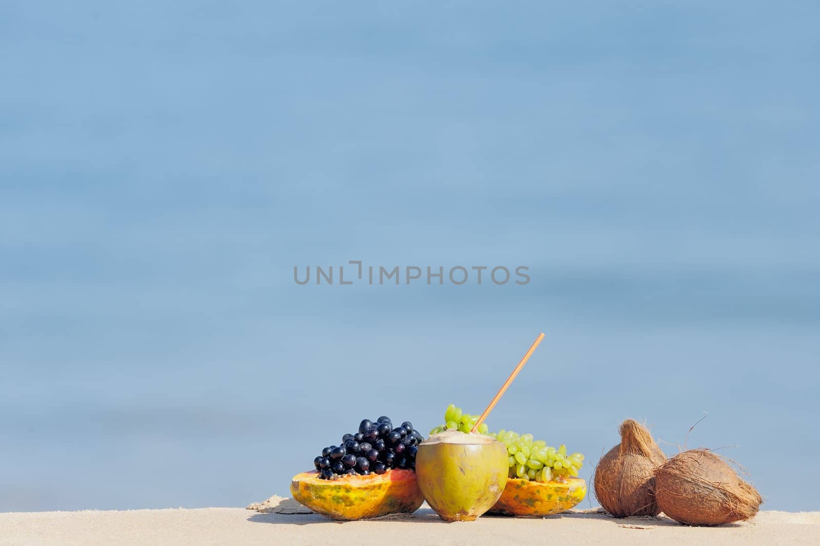 Papaya, coconut, nut and grapes on the sandy beach