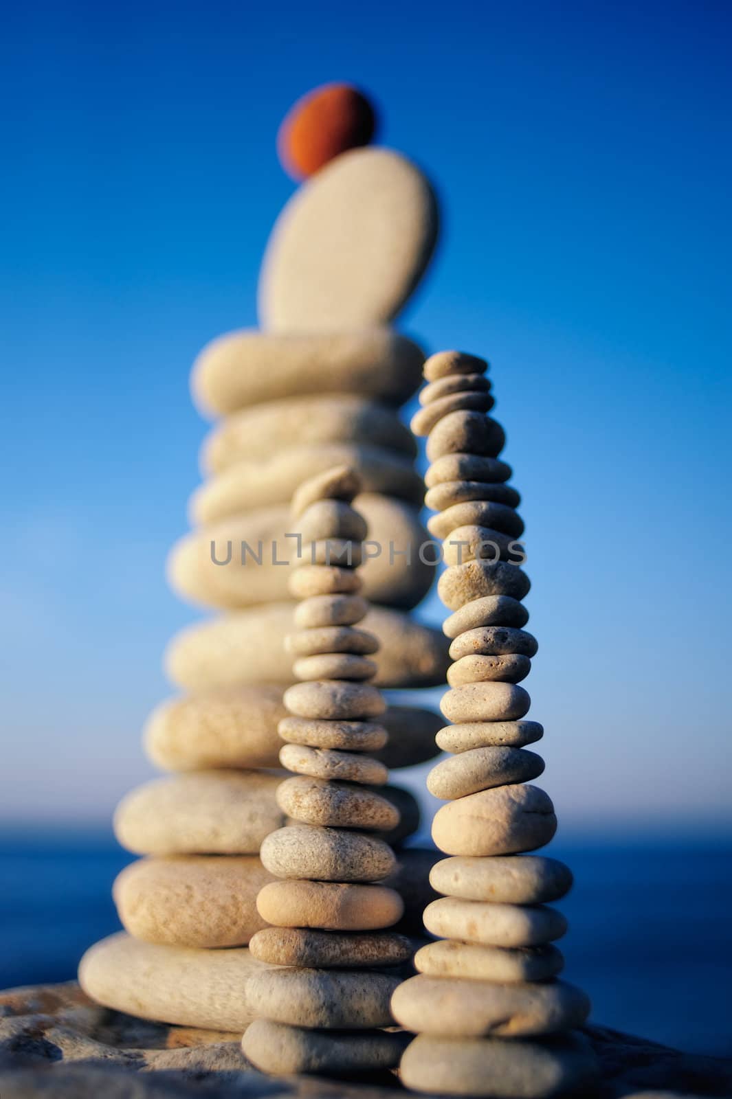 Balancing red stone on the top of pile of pebbles