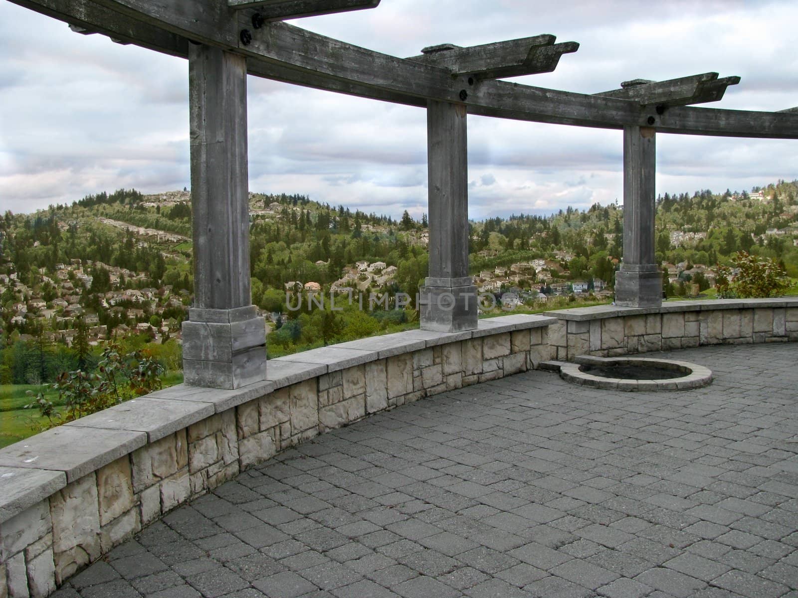 A courtyard with columns with a residentially settled hillside in the distance.