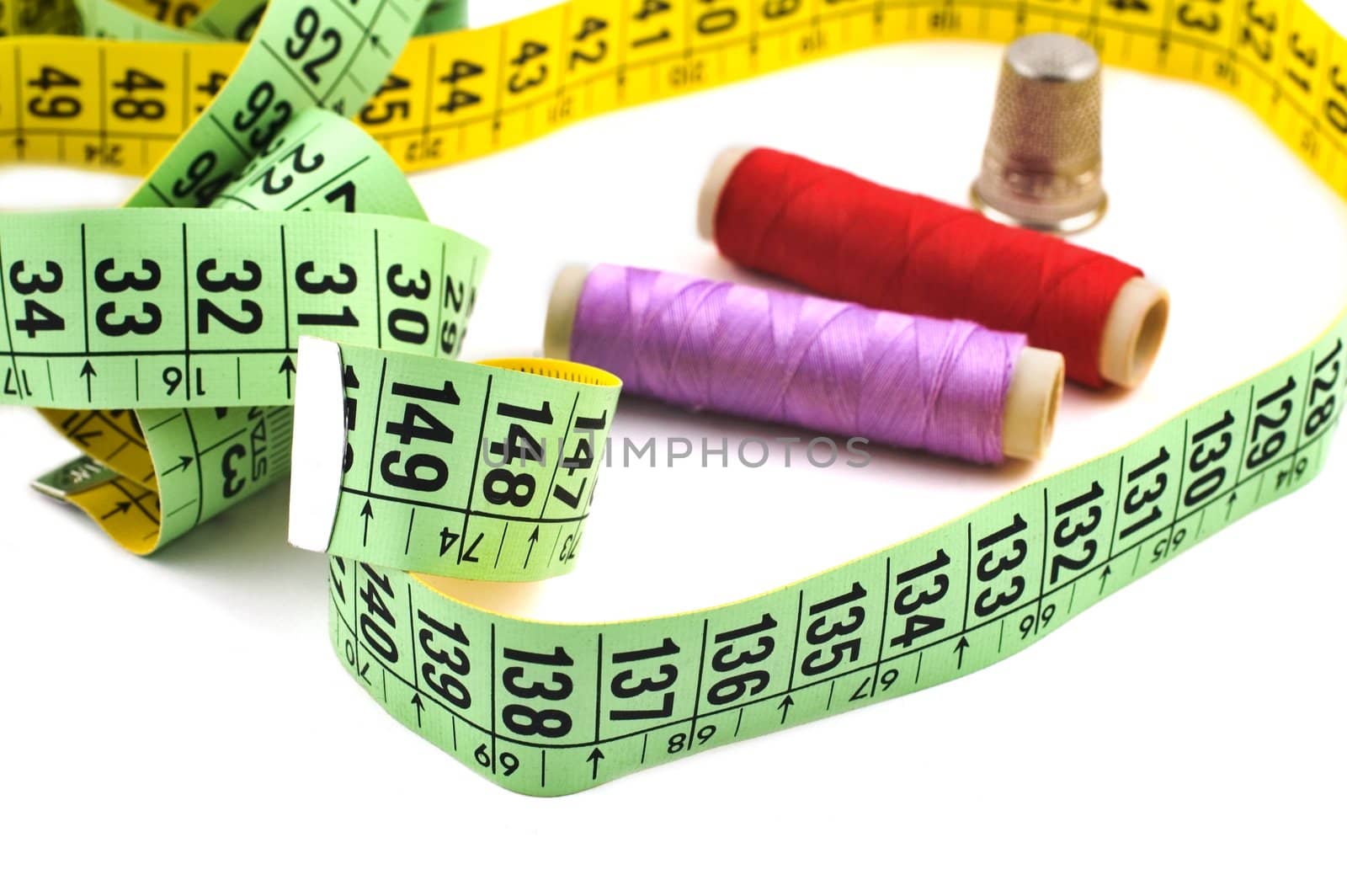 Green and yellow meter with colored sewing spools isolated on white with selective focus