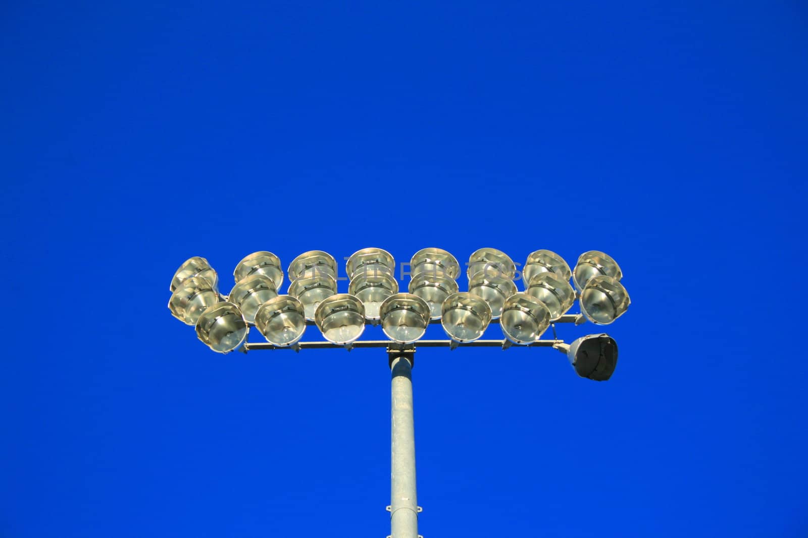 Close up of stadium lights over blue sky.
