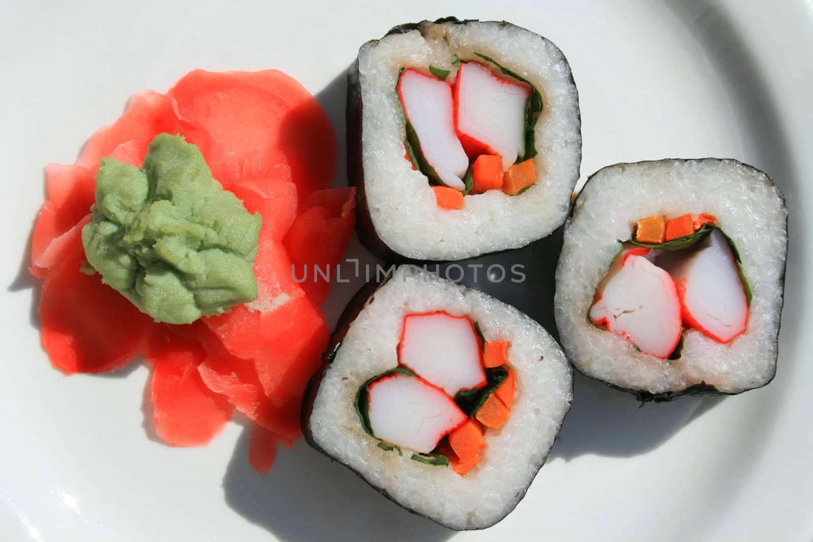 Sushi next to wasabi and sushi ginger on a platter.
