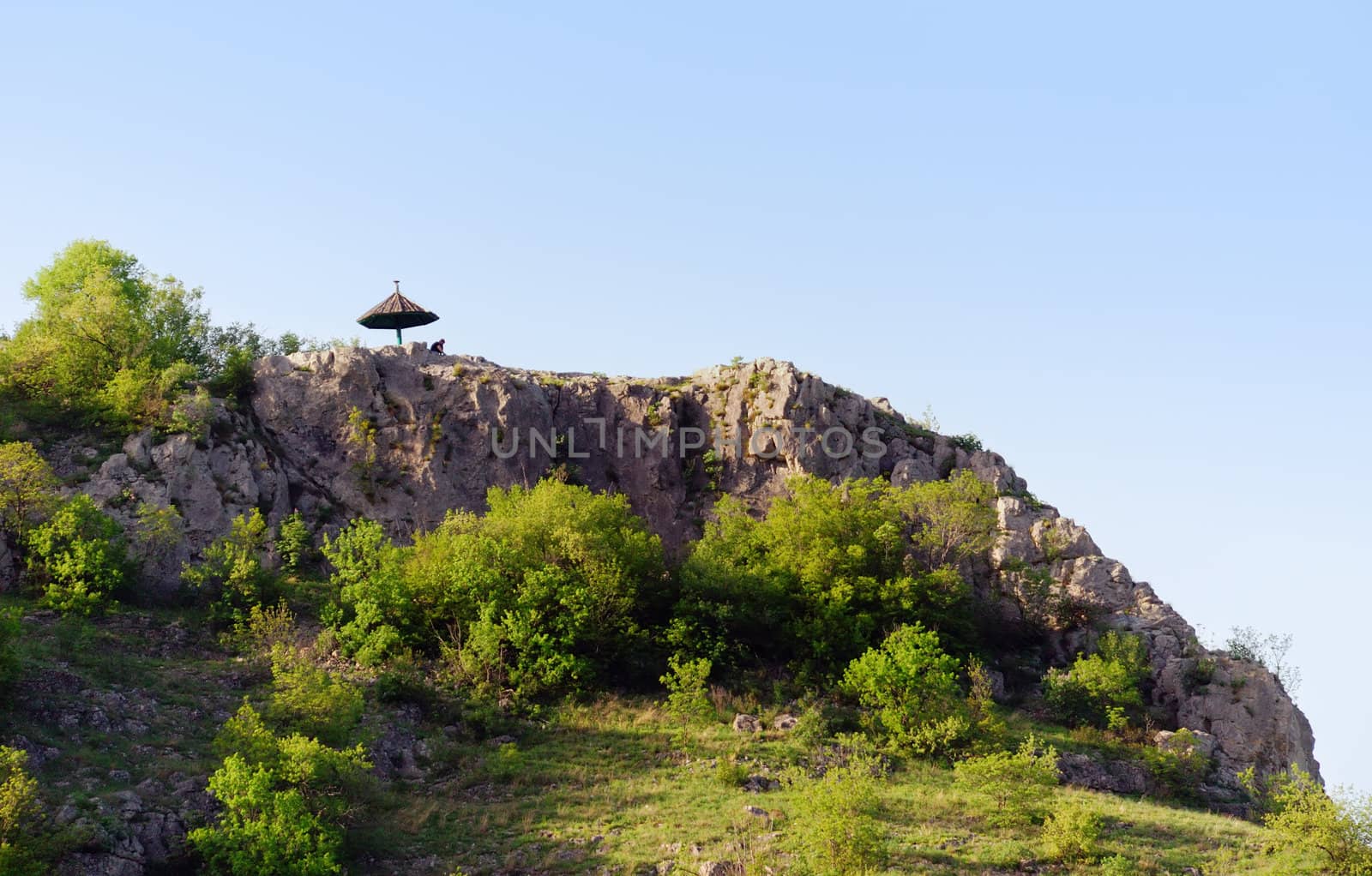 a man under umbrella on the top of a rock