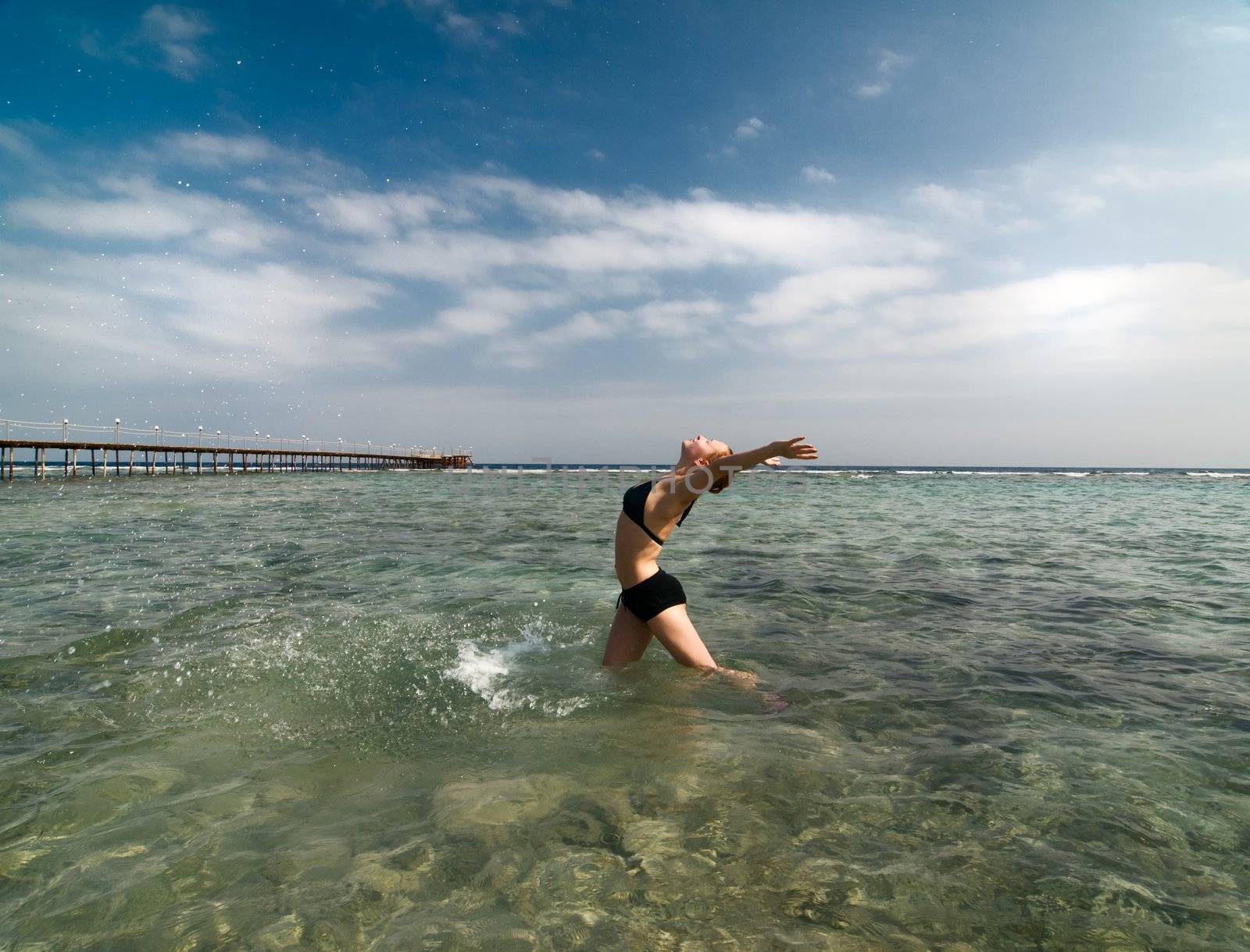 Young woman enjoying the sun standing in water