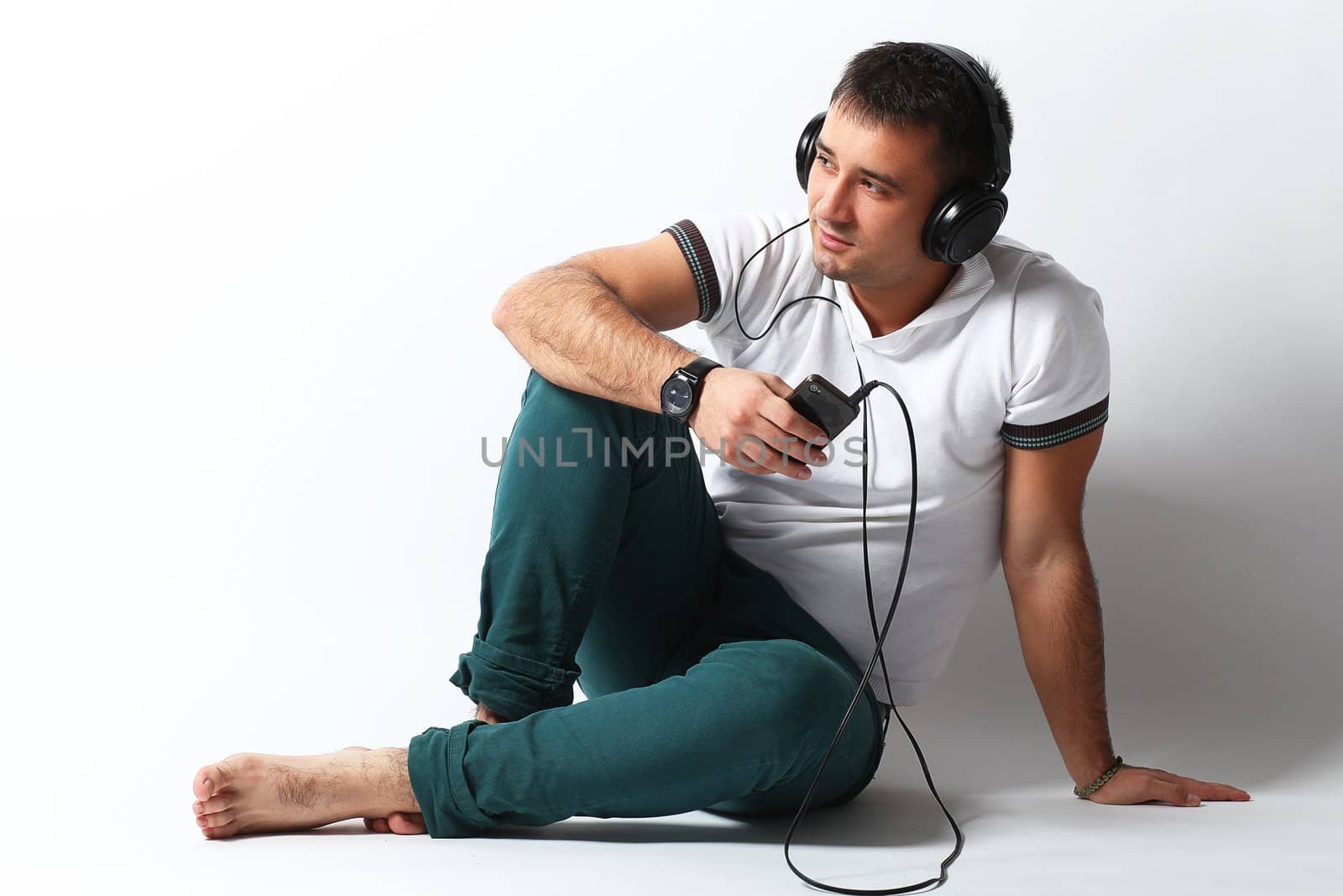 Handsome guy listening music sitting over white background