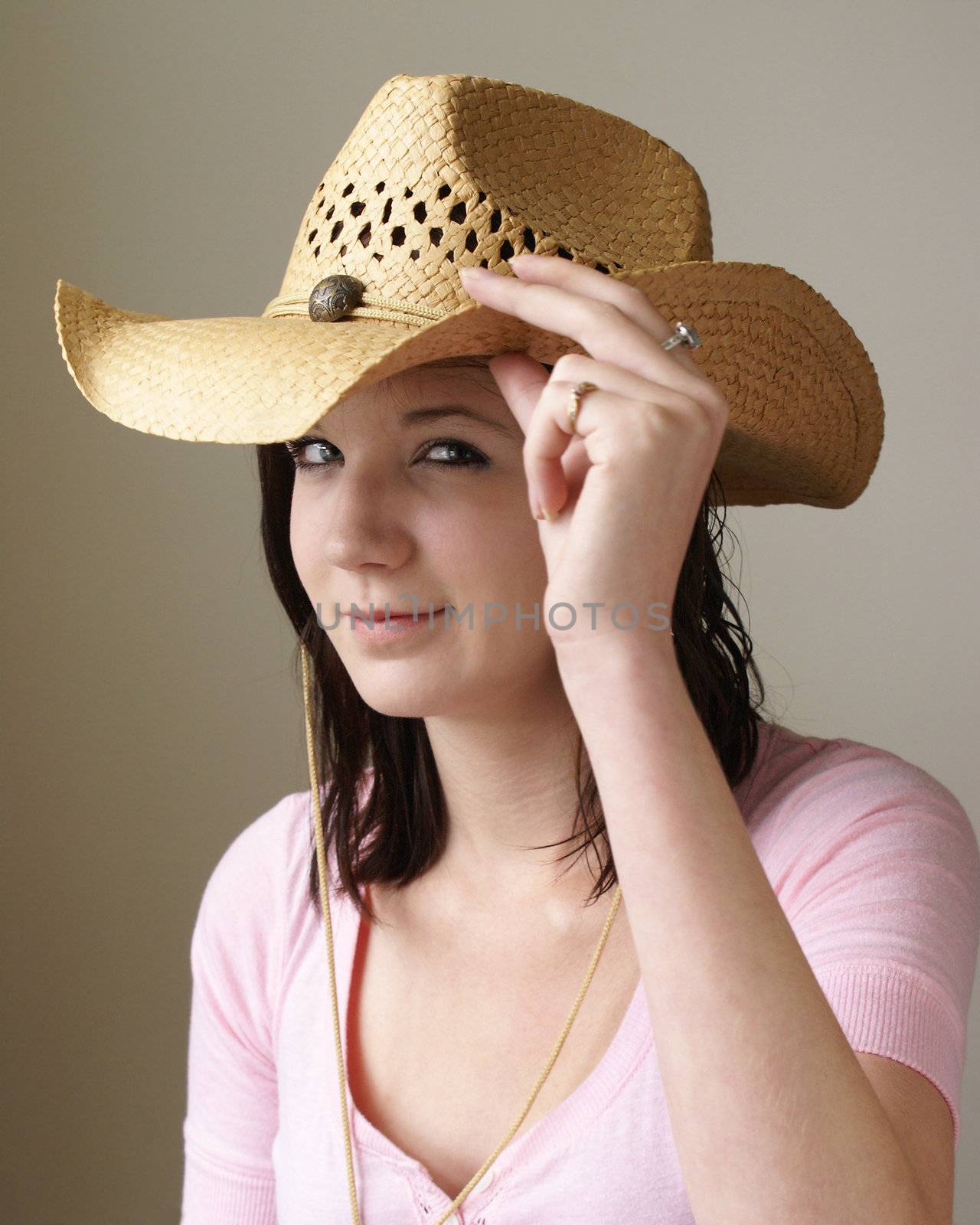 A young girl is tipping her straw hat in this casual portrait.