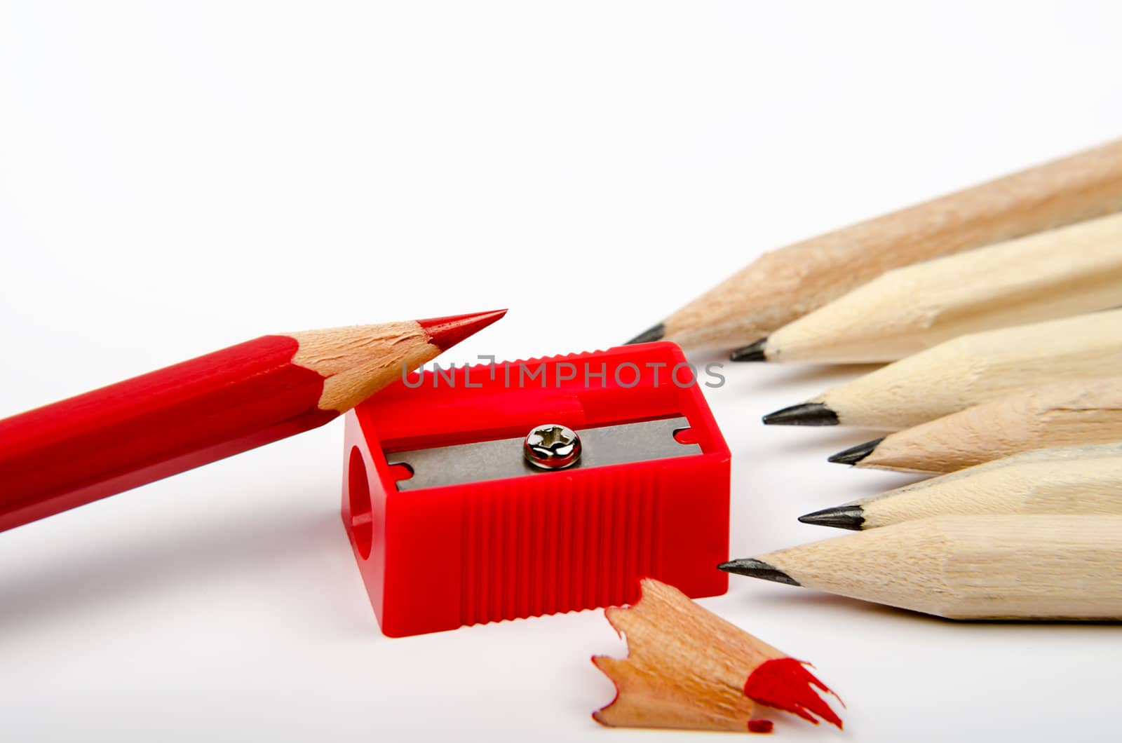 Group of wooden pencils and red sharpener on white background
