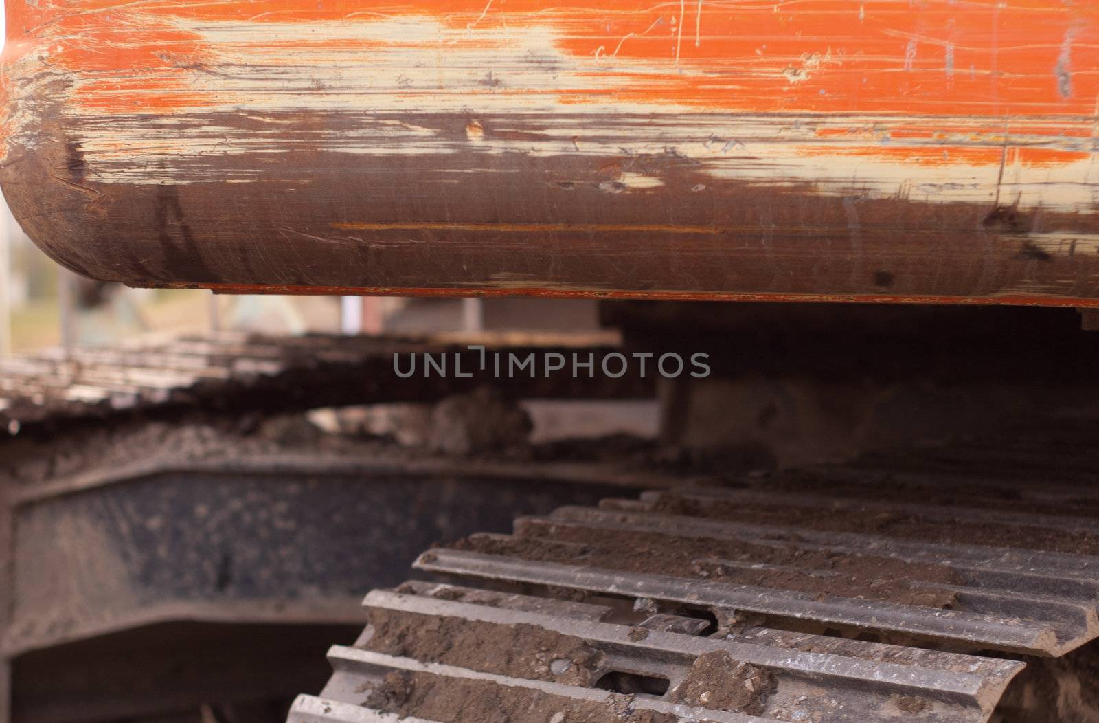 tracks and the back of an orange trackhoe very scratched and used