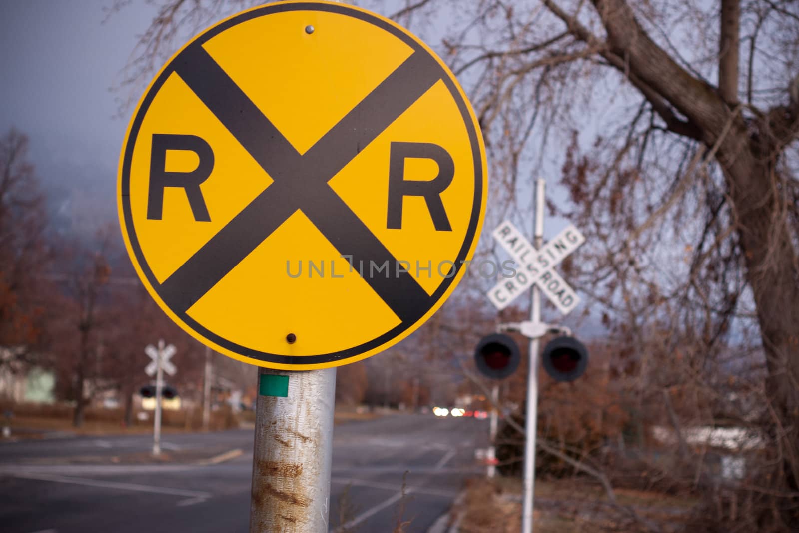 yellow railroad crossing sign with crossing sign in background