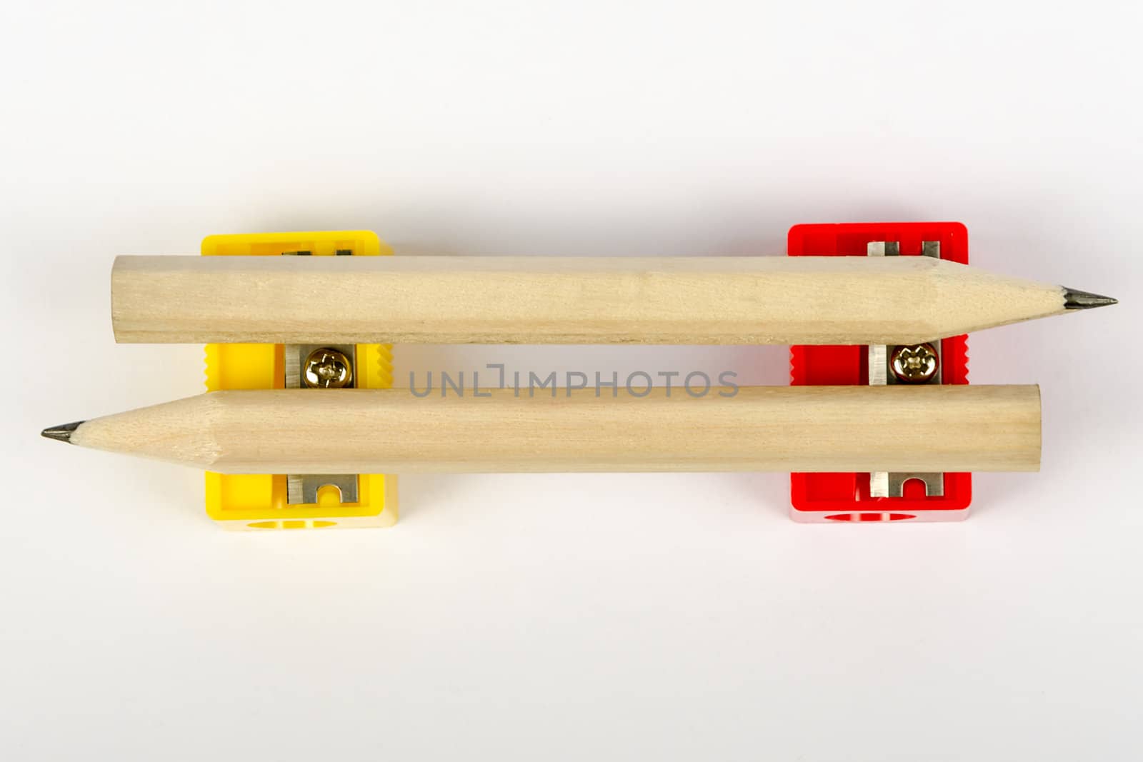 Two wooden pencils with sharpeners red and yellow on a white background