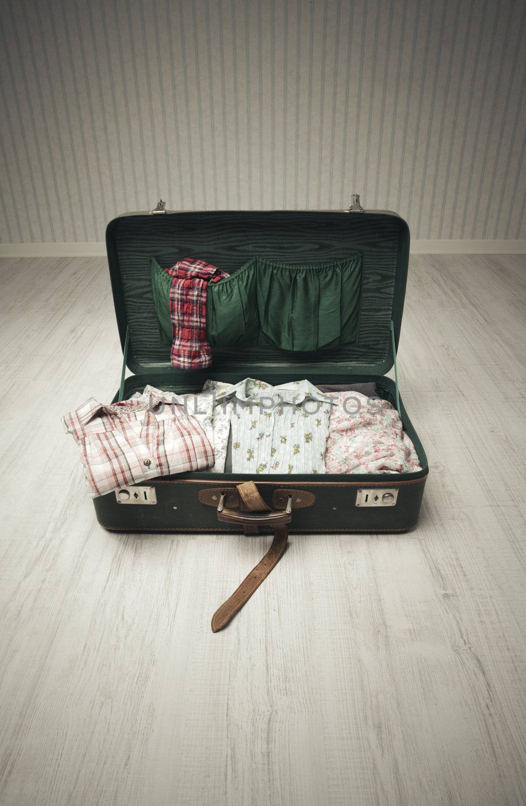 Vintage suitcase open on a wood floor in an empty room