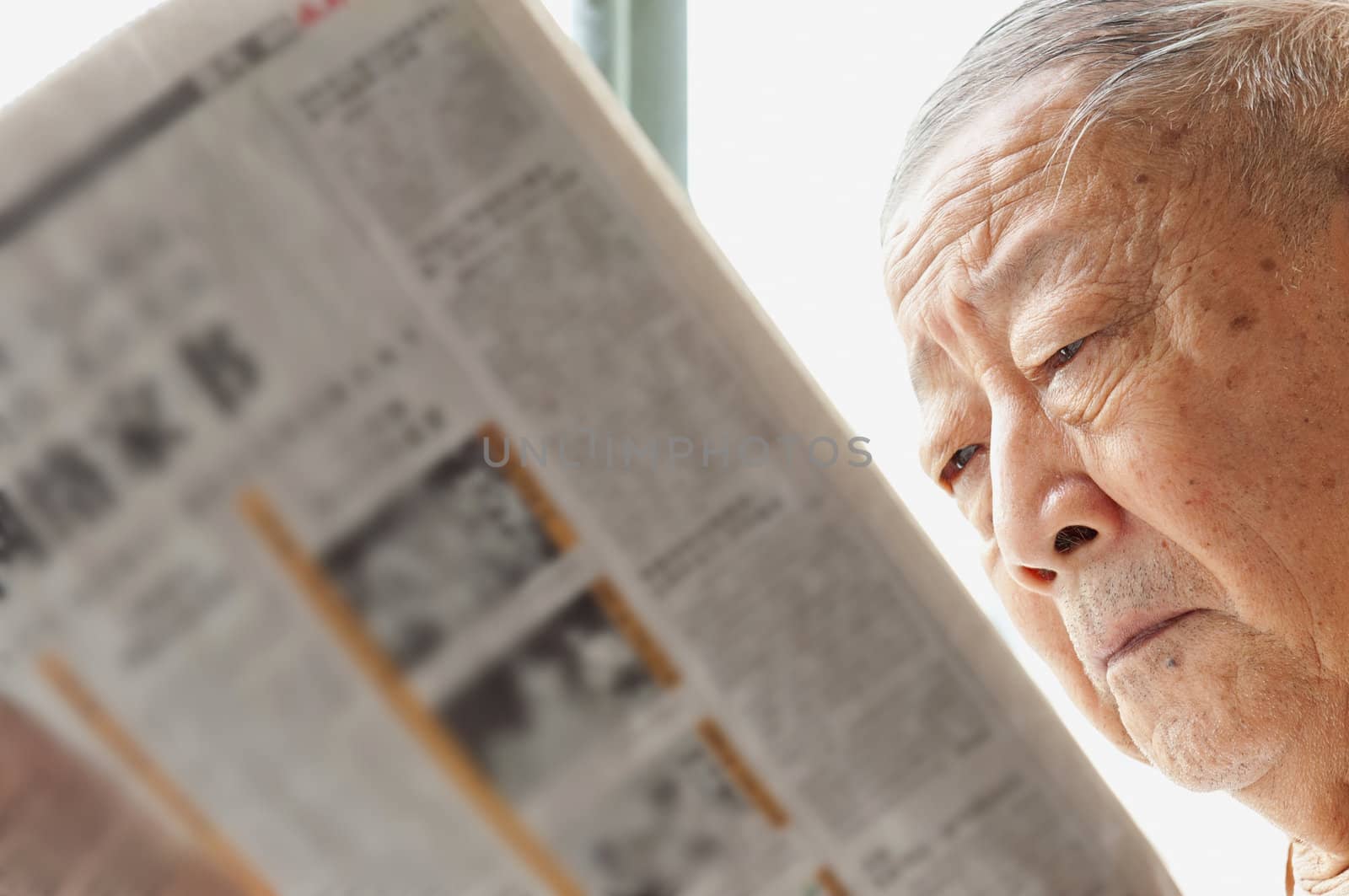 a senior man is reading newspaper by jackq