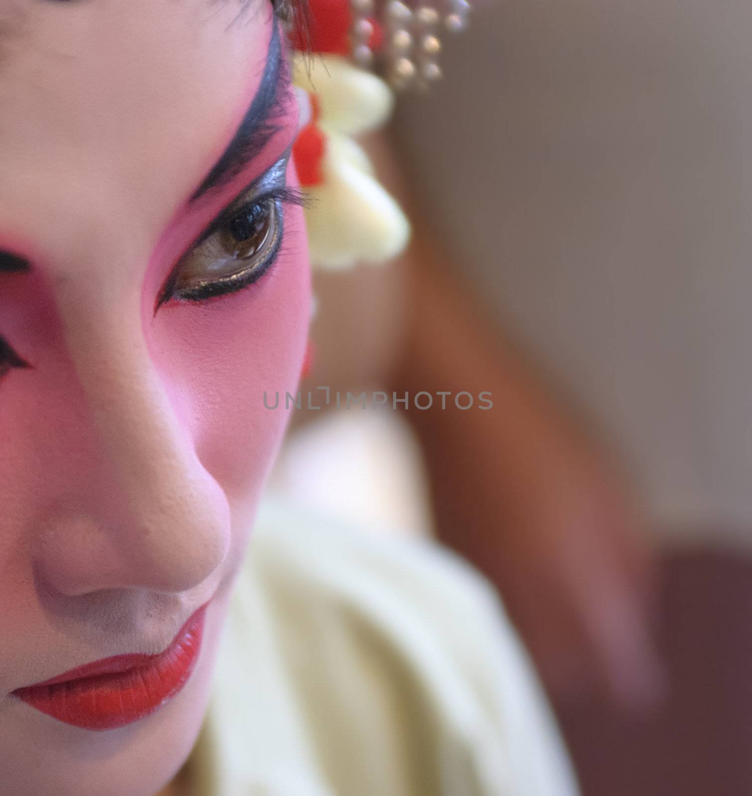 a chinese opera actress is painting her face backstage.