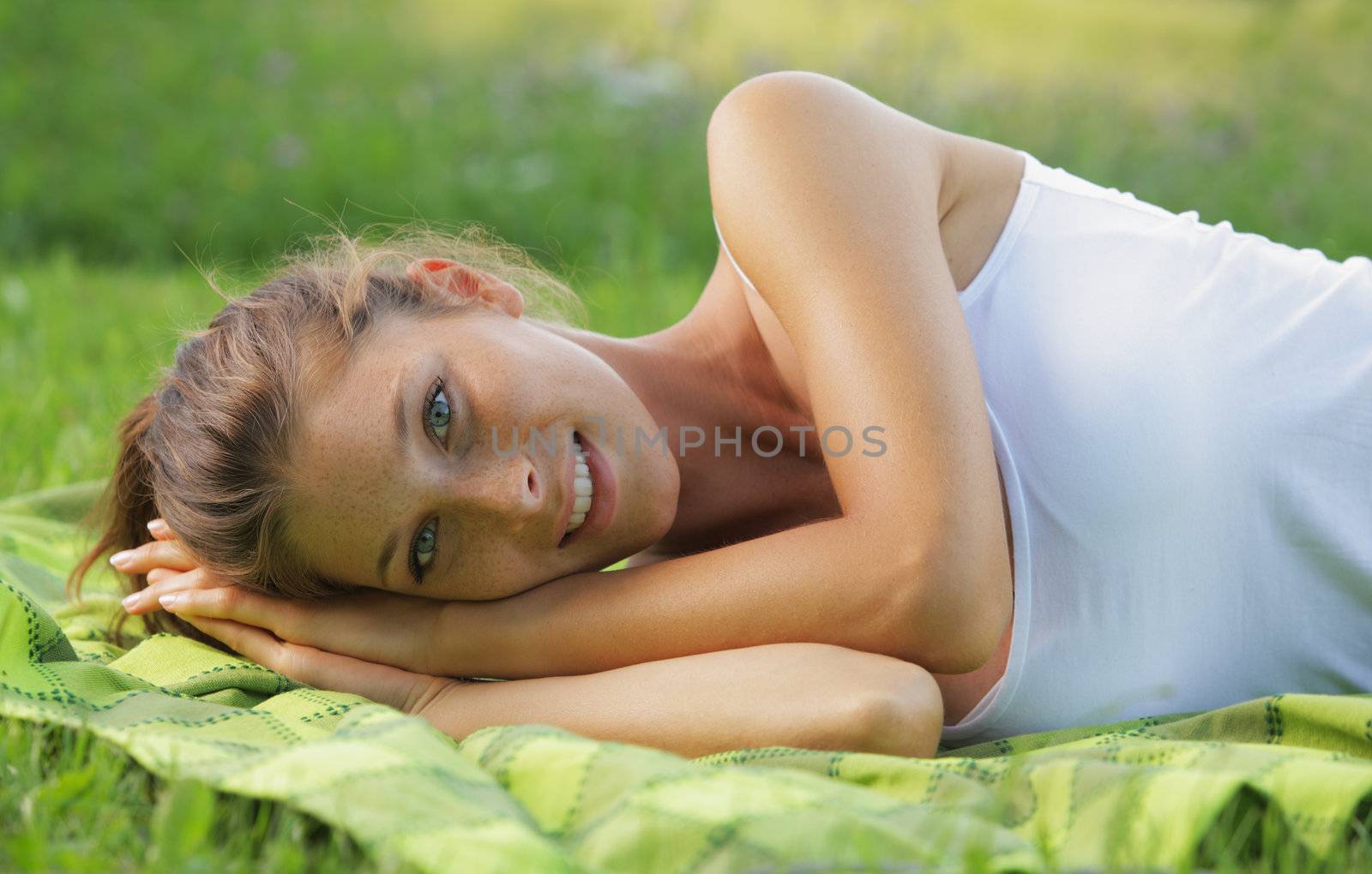 Beautiful smiling woman laying on the grass 