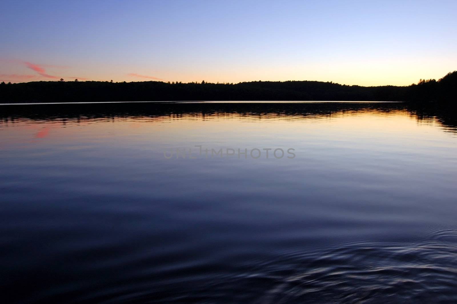 Sunset and canoe trip in calm lake in Algonquin Park