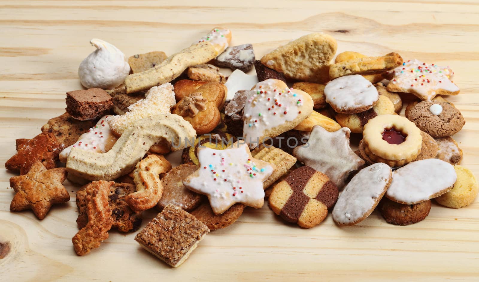 Stack of various brown biscuits and cookies on a wooden table.