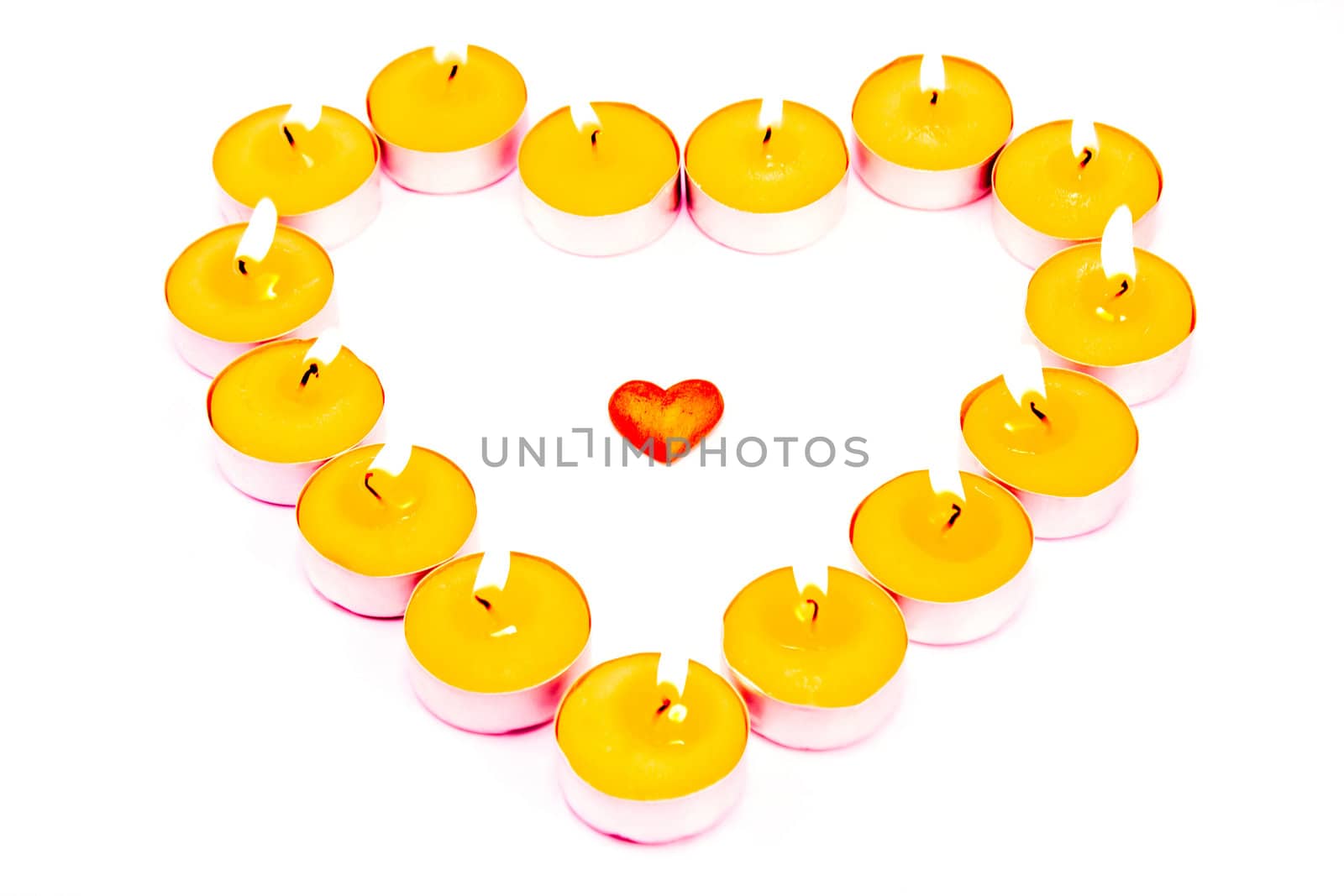 Heart surrounded with burning candles isolated on white