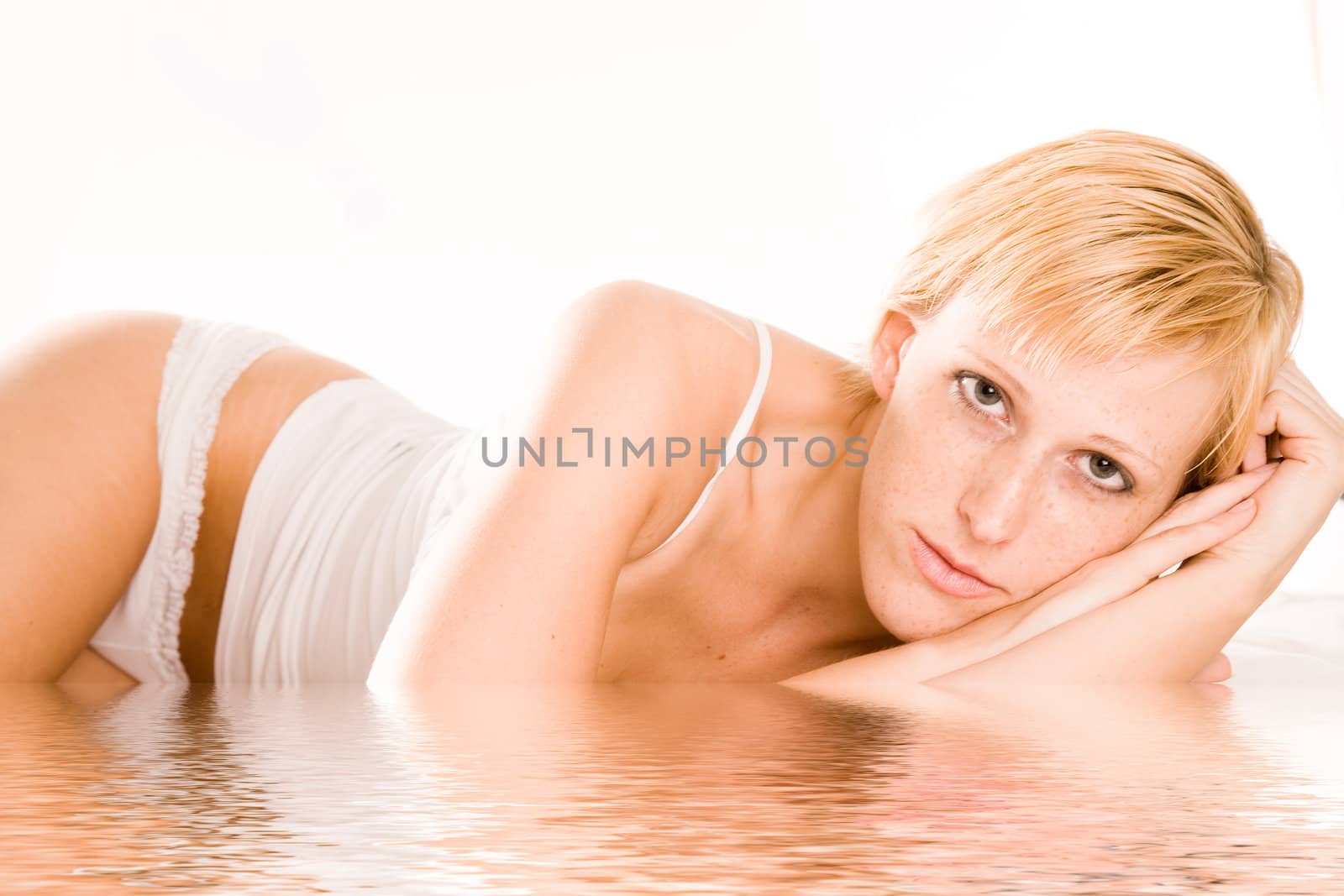 Studio portrait of a blond short haired girl in lingerie laying on her bed