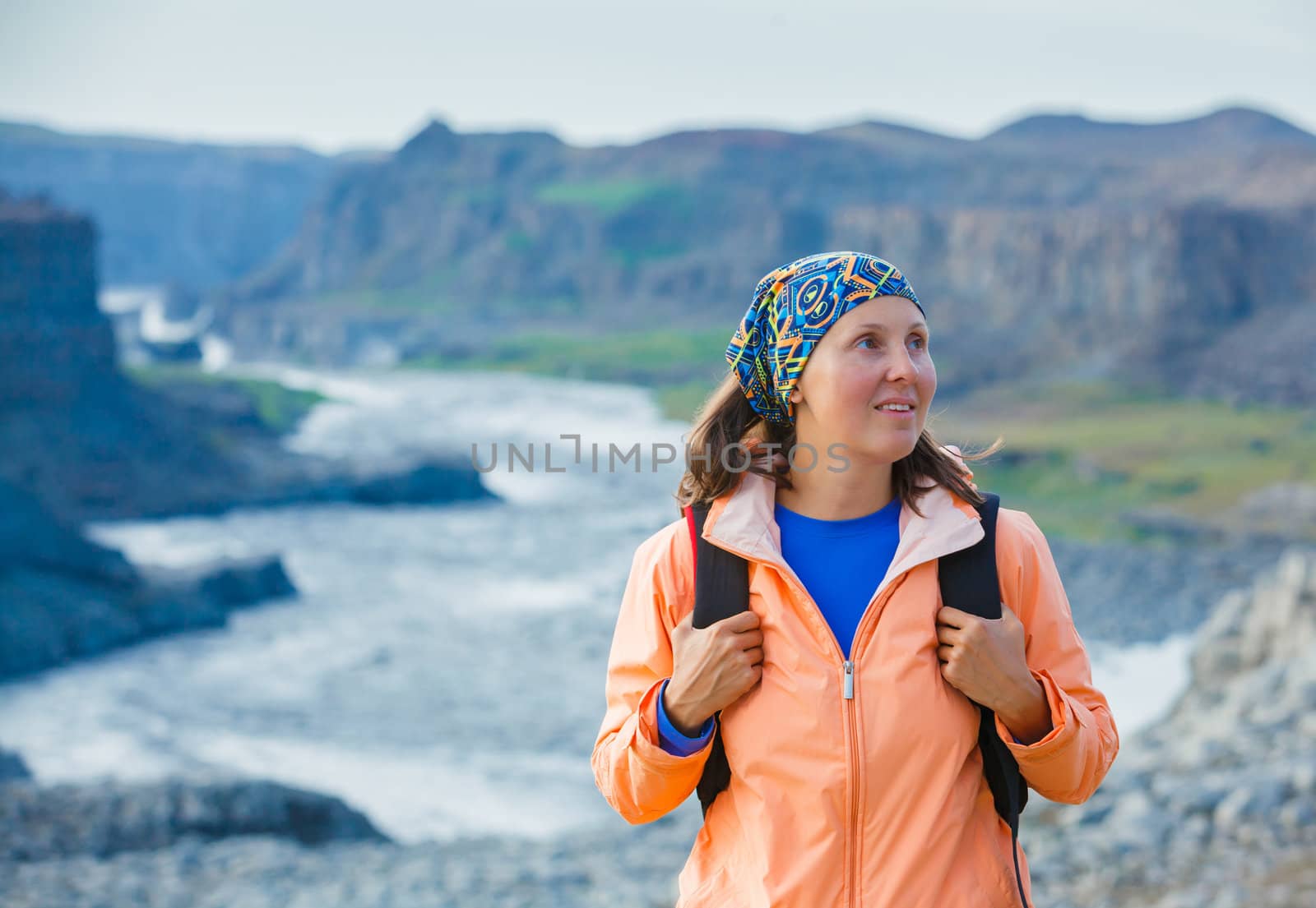 Cute woman hiking in the canyon Dettifoss waterfall in Vatnajokull National Park, Northeast Iceland.