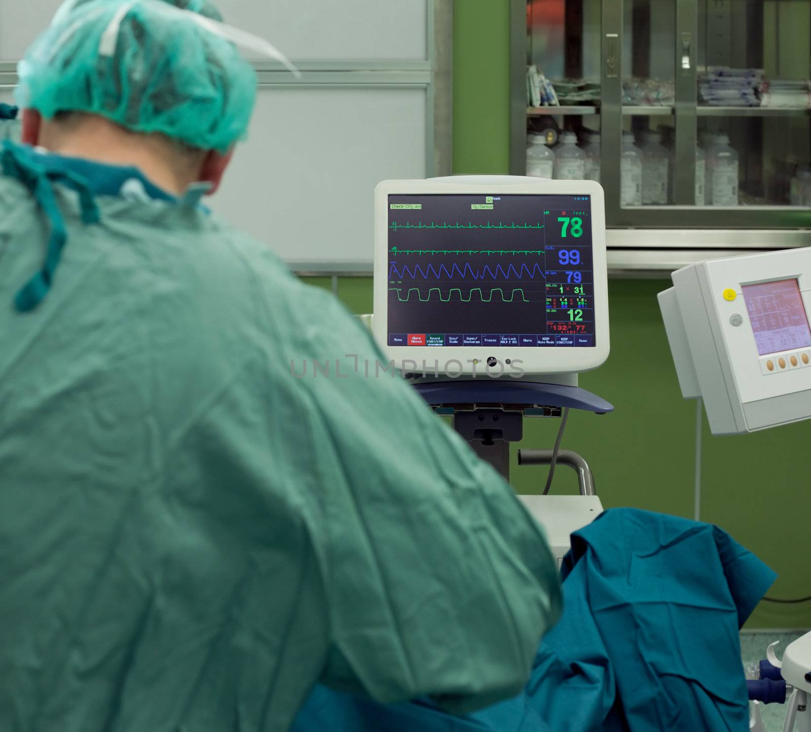cardiogram monitor in surgery while doctor operates on patient