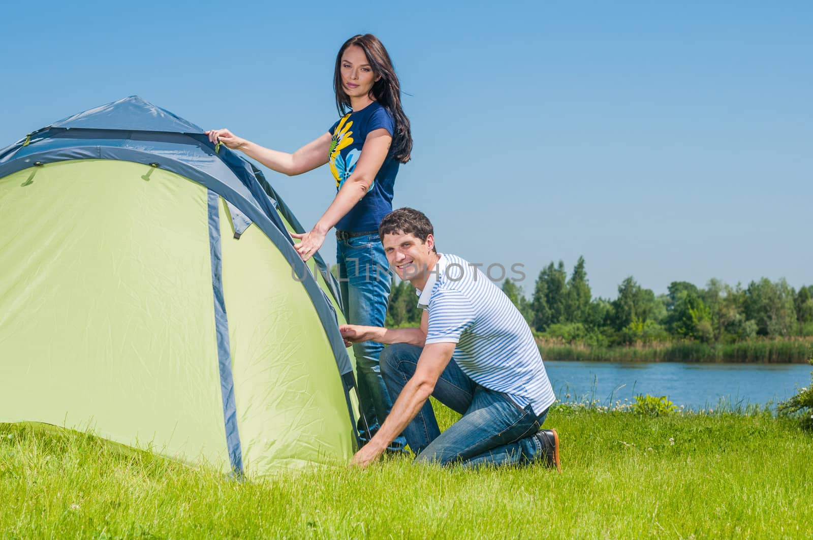 Holiday camping - Man And Woman Couple Setting Up Tent In The Countryside