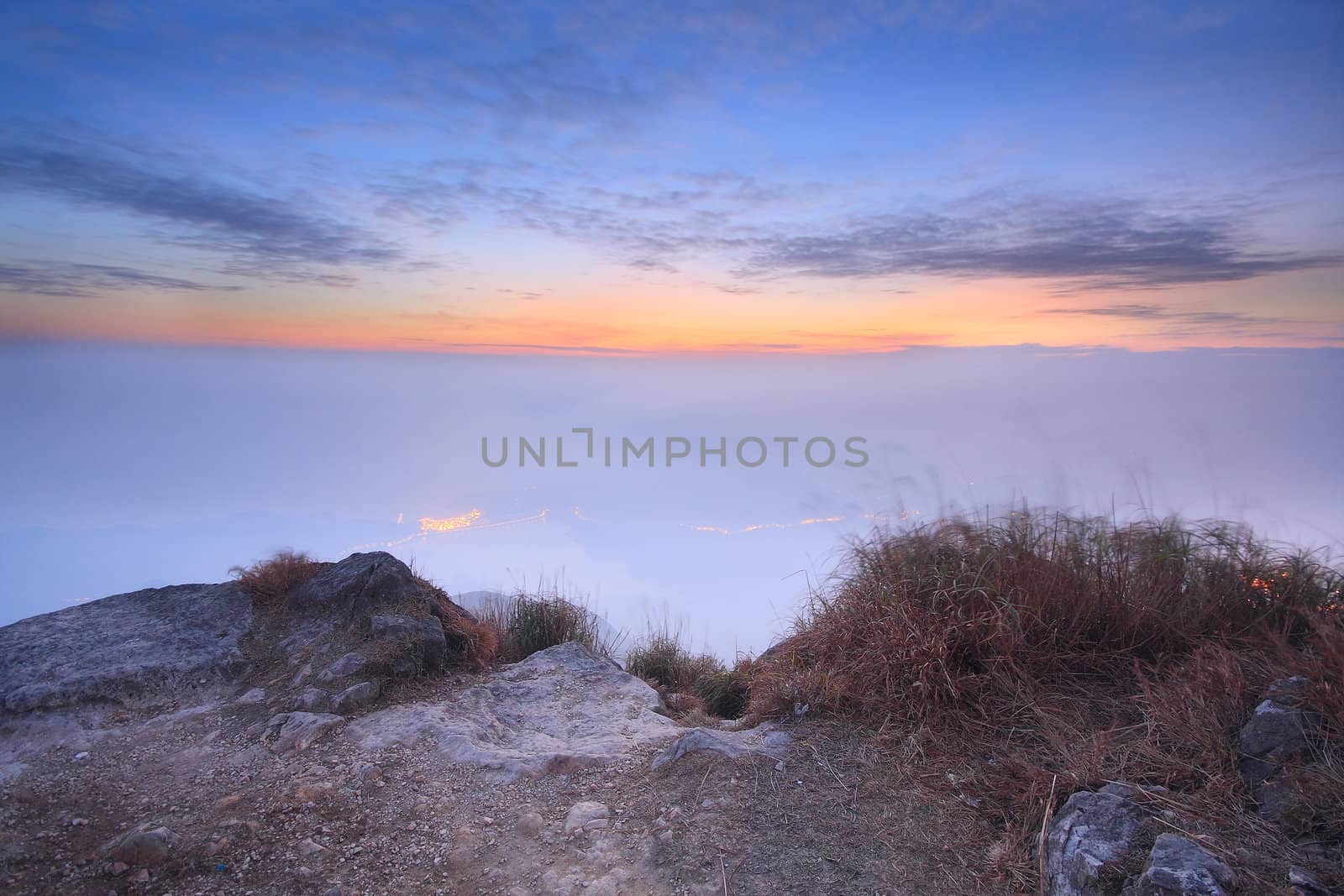 dark landscape with fog between hills and orange sky before sunrise 