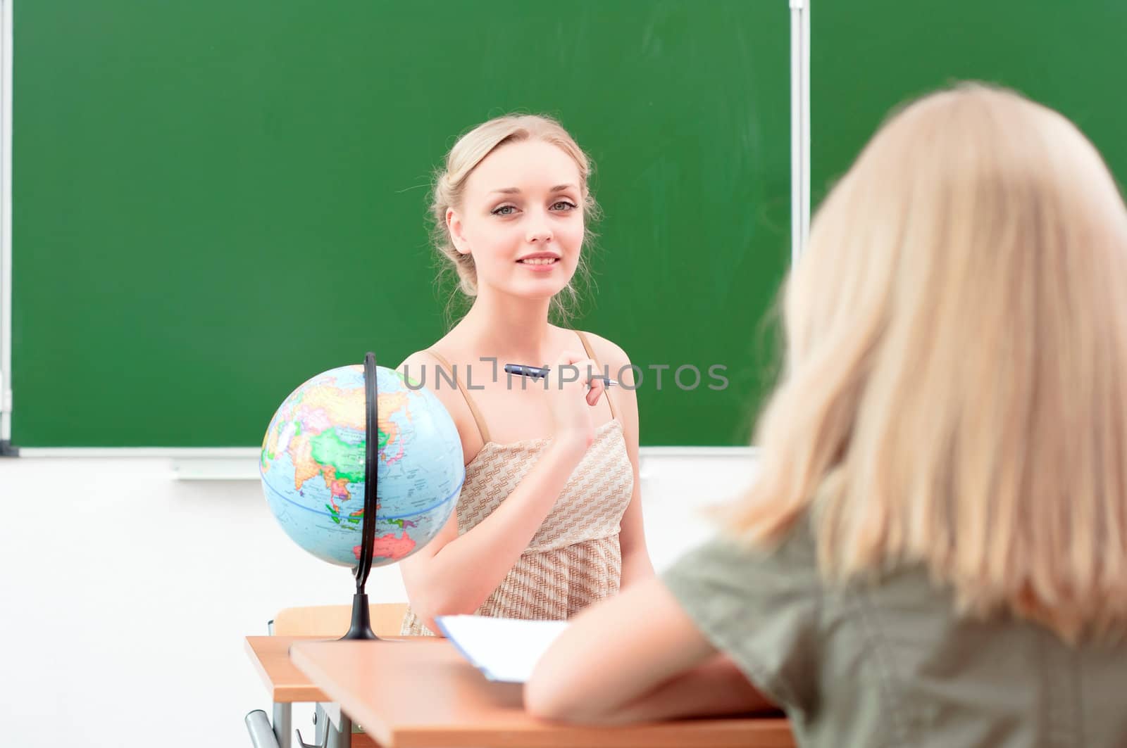 portrait of beautiful young teacher, sits at a desk in the classroom