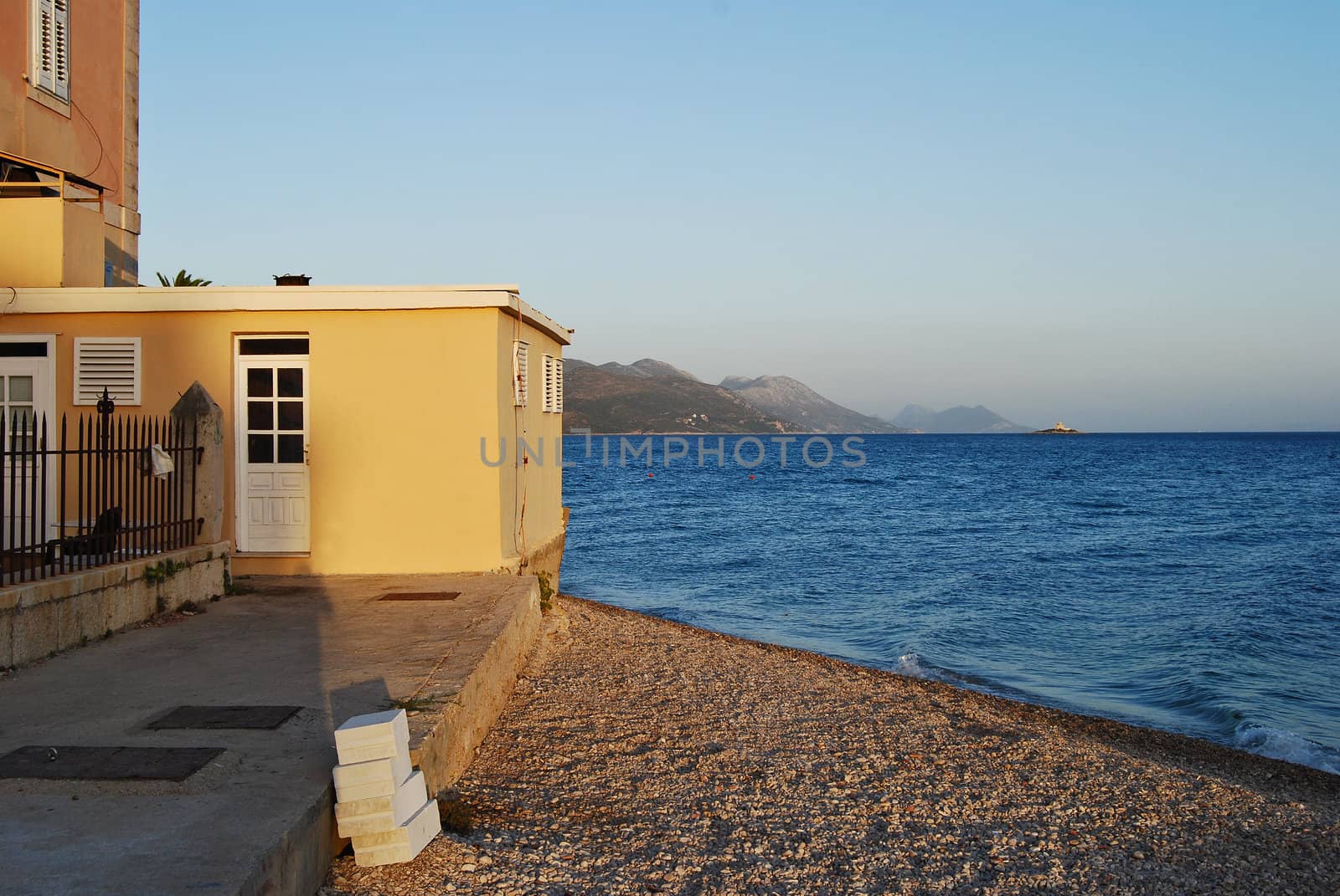 Yellow house,gravel shore,sea,sky