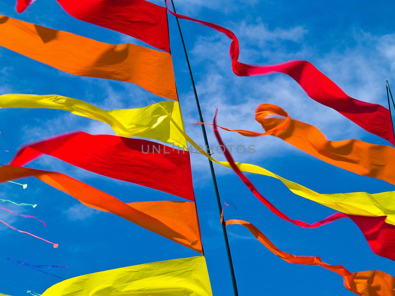 Red, Orange, and Yellow Flags Waving in a Blue Sky