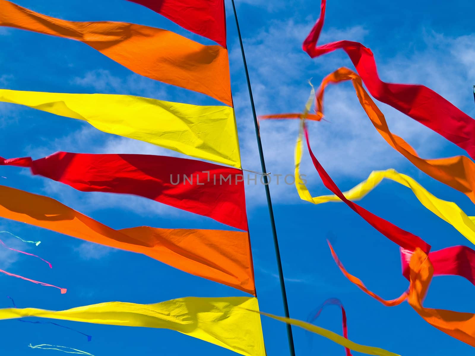 Red, Orange, and Yellow Flags Waving in a Blue Sky by Frankljunior