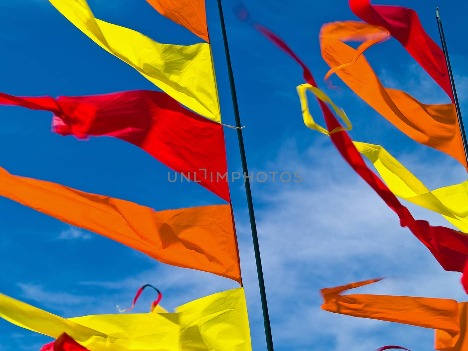 Red, Orange, and Yellow Flags Waving in a Blue Sky by Frankljunior